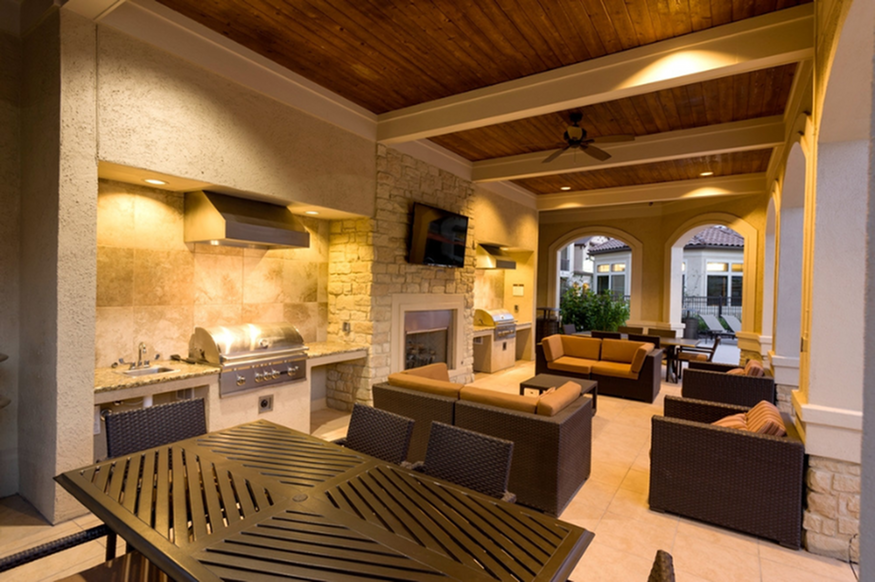 Elegant outdoor terrace featuring a cozy seating area, modern grill, and beautiful stone fireplace with warm lighting.