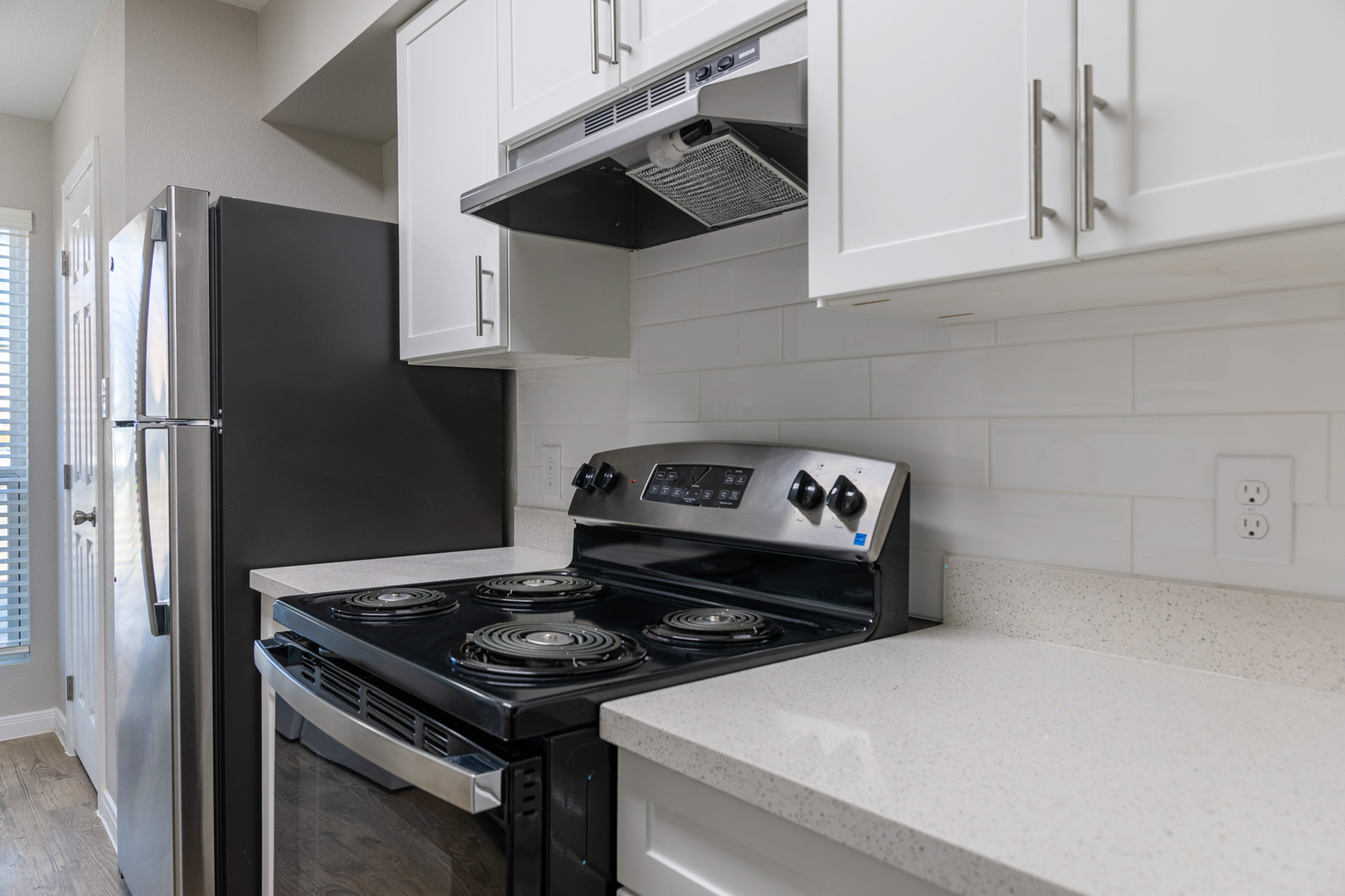 Modern kitchen with sleek stainless steel appliances, polished quartz countertops, and white cabinetry for a fresh, contemporary look.