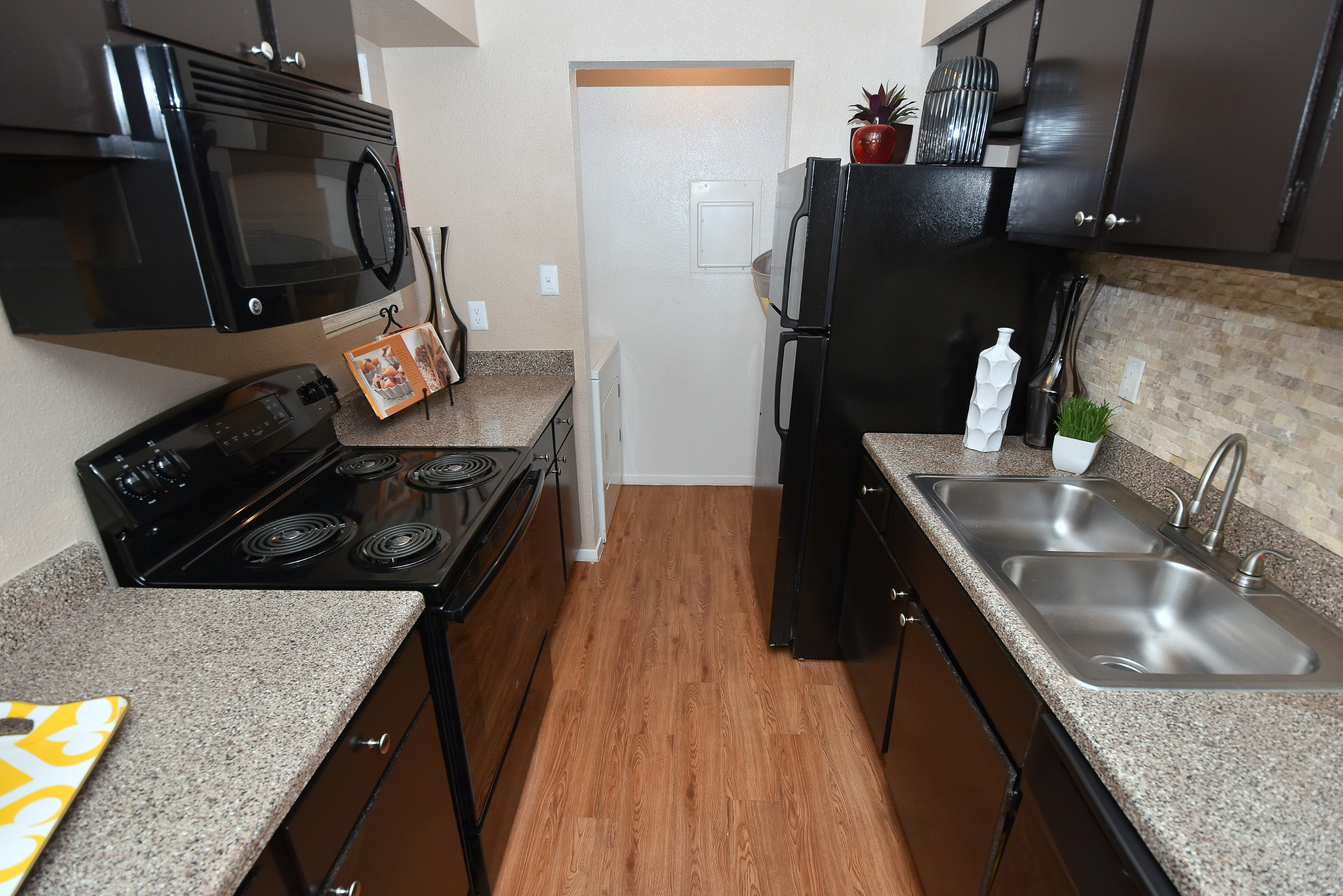 Modern kitchen with sleek black appliances, elegant countertops, and rich wood flooring for a sophisticated touch.