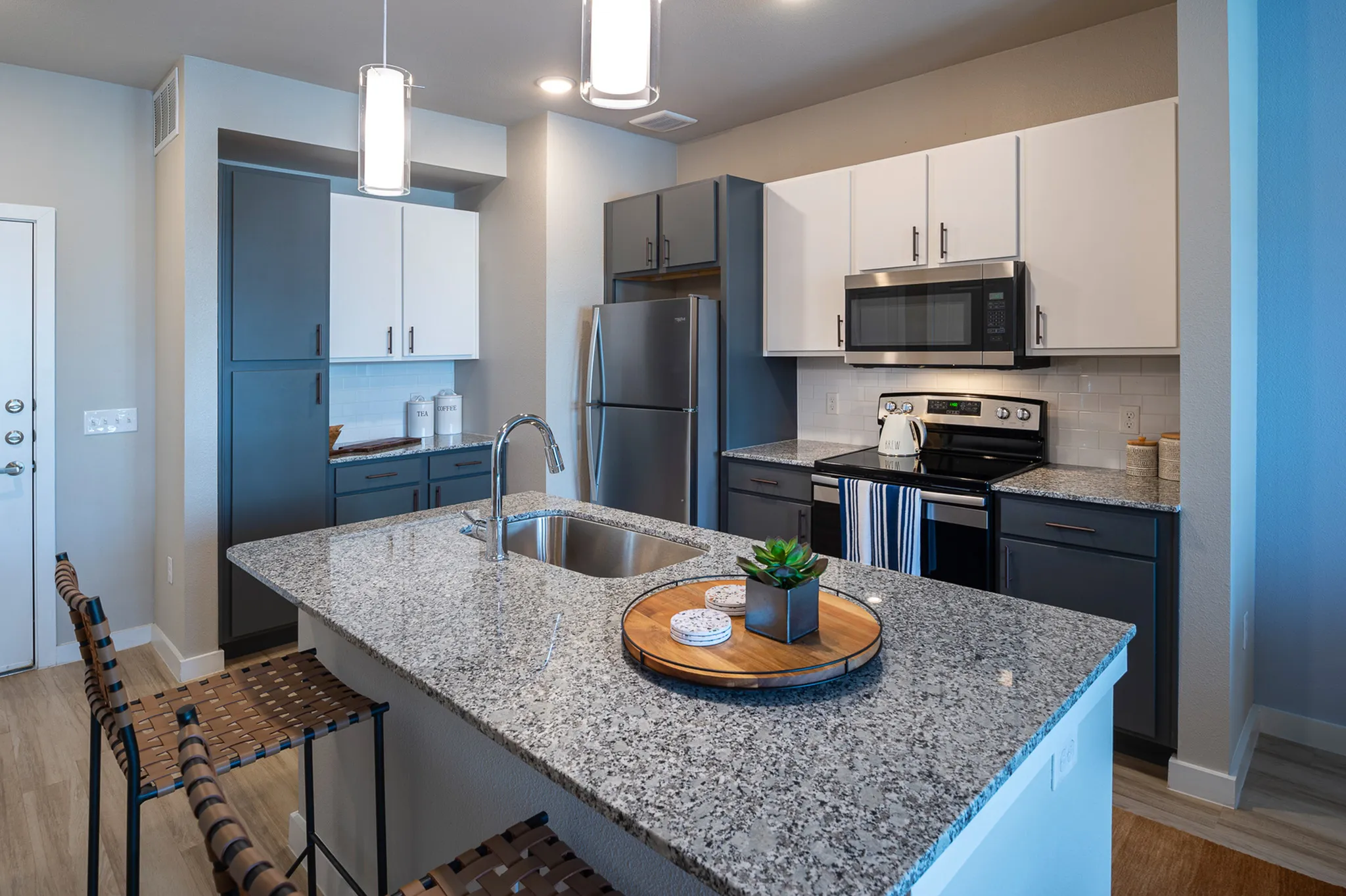 Modern kitchen with elegant granite countertops, stainless steel appliances, and chic bar seating, ideal for entertaining.