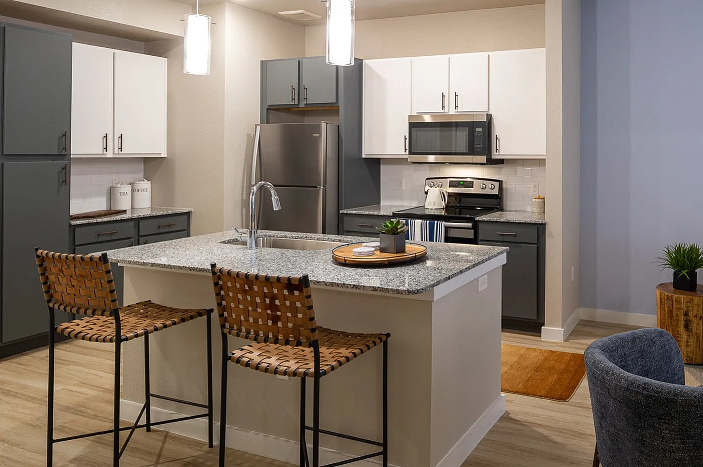 Contemporary open-plan apartment featuring a chic kitchen with granite countertops, stylish bar seating, and a cozy living room with modern decor and vibrant artwork.