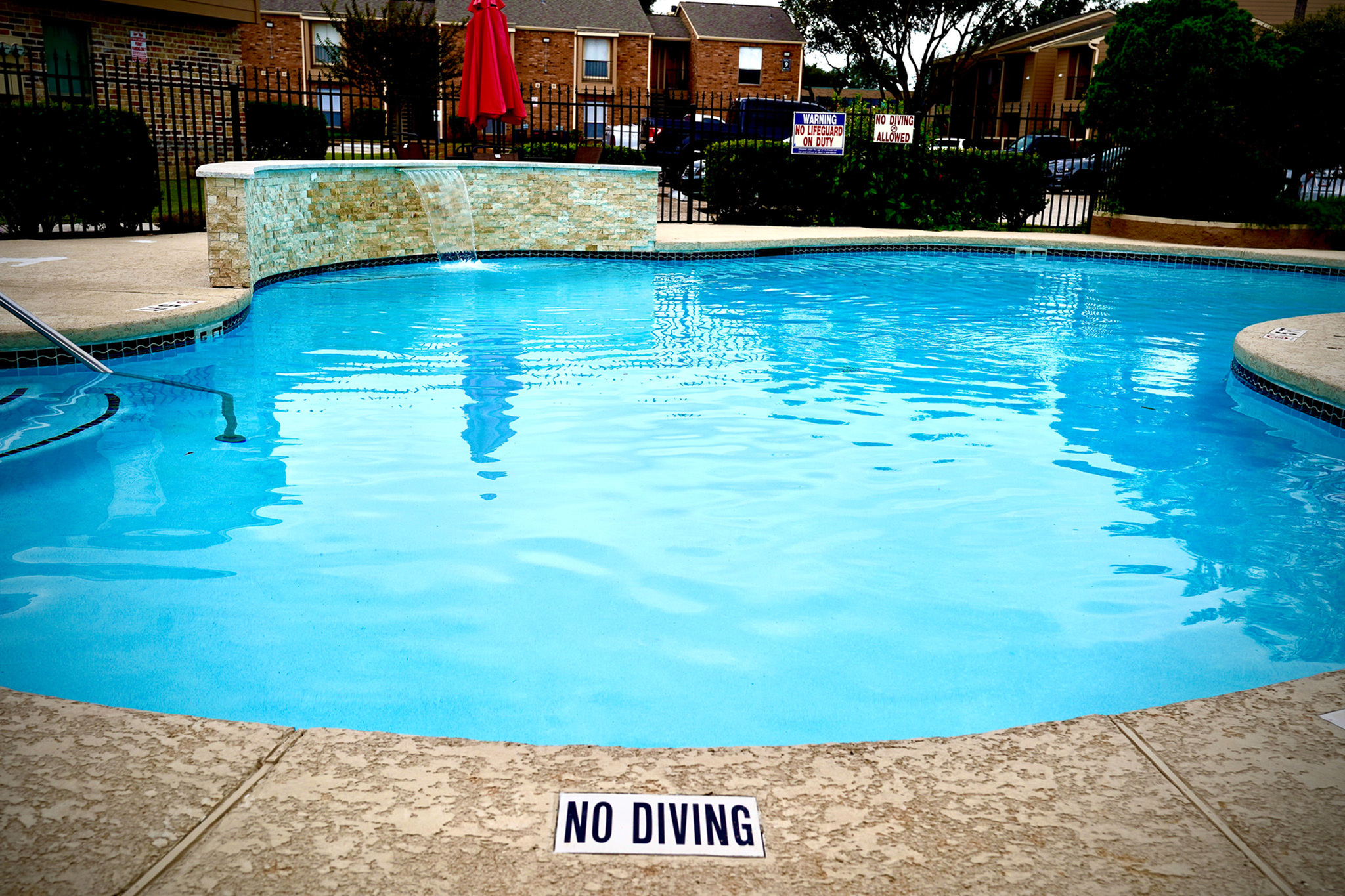 Inviting swimming pool area with calming waterfall feature, perfect for relaxation and leisure in a serene residential complex.