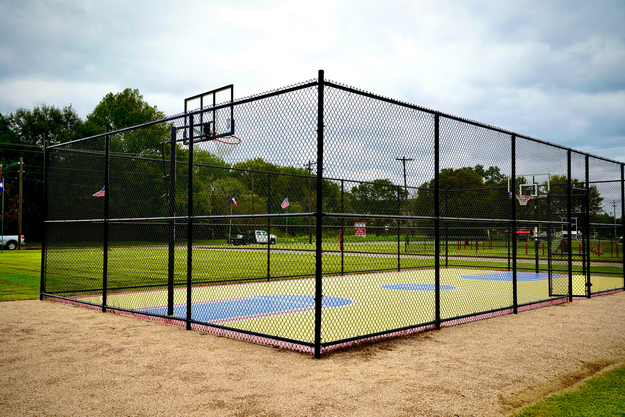 Inviting outdoor basketball court with vibrant painted lines, surrounded by lush greenery, perfect for recreational fun.