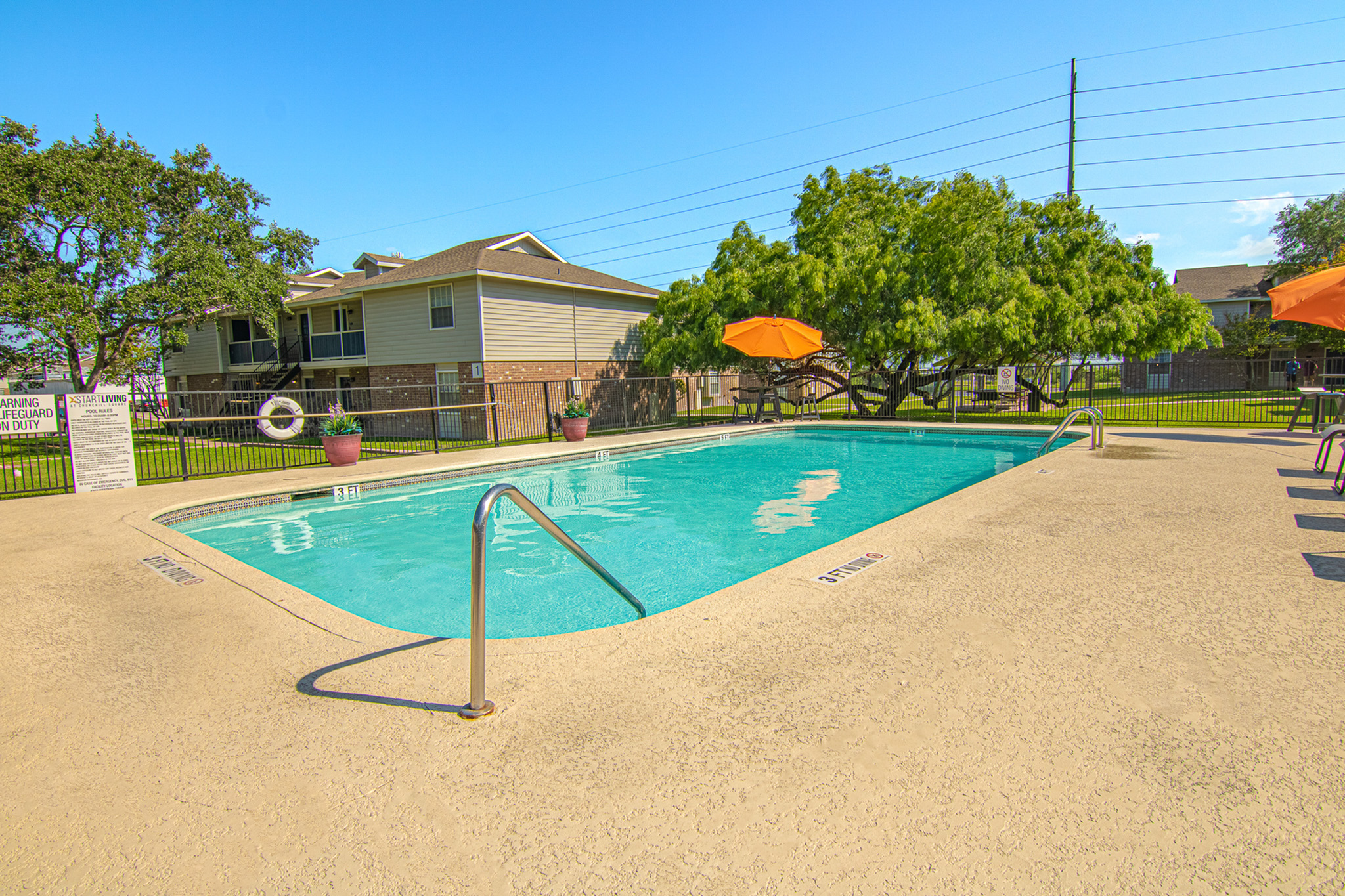 Charming outdoor swimming pool area with vibrant orange umbrellas and well-maintained greenery, perfect for relaxation and leisure.