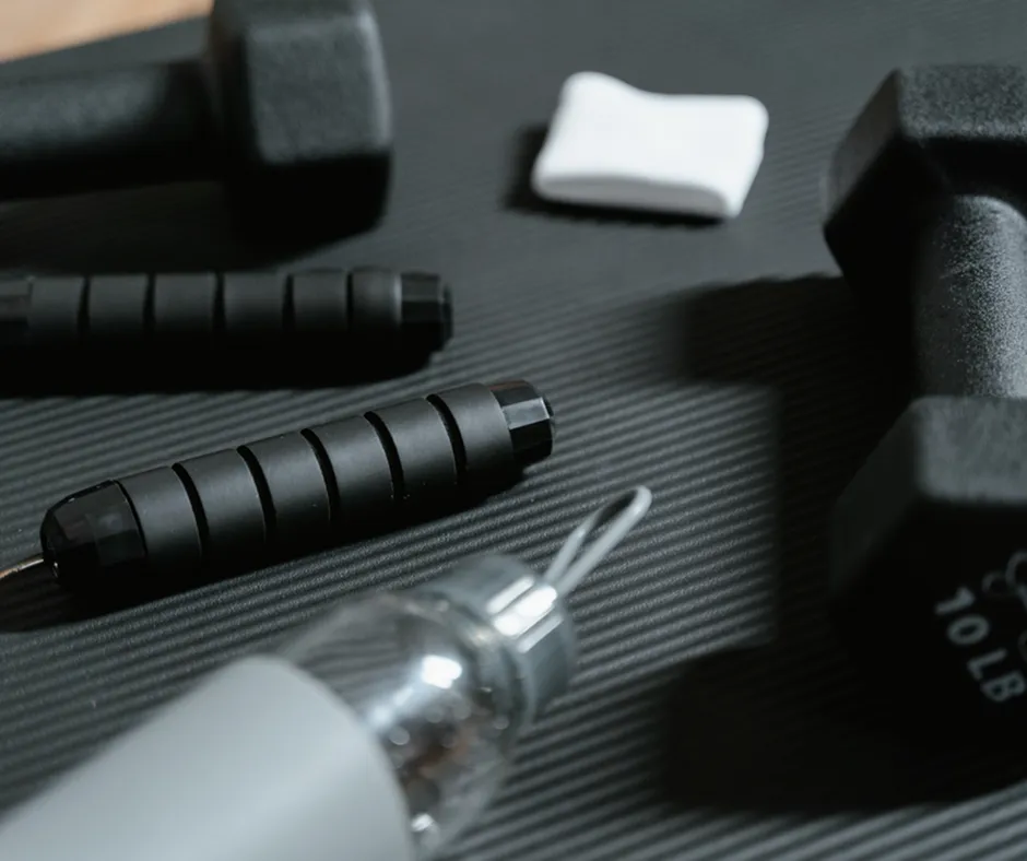 Inviting home gym space featuring sleek dumbbells, a jump rope, and a hydration bottle on a textured exercise mat.