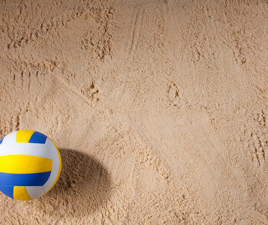 Vibrant volleyball resting on pristine sand, ready for an exciting beach game.