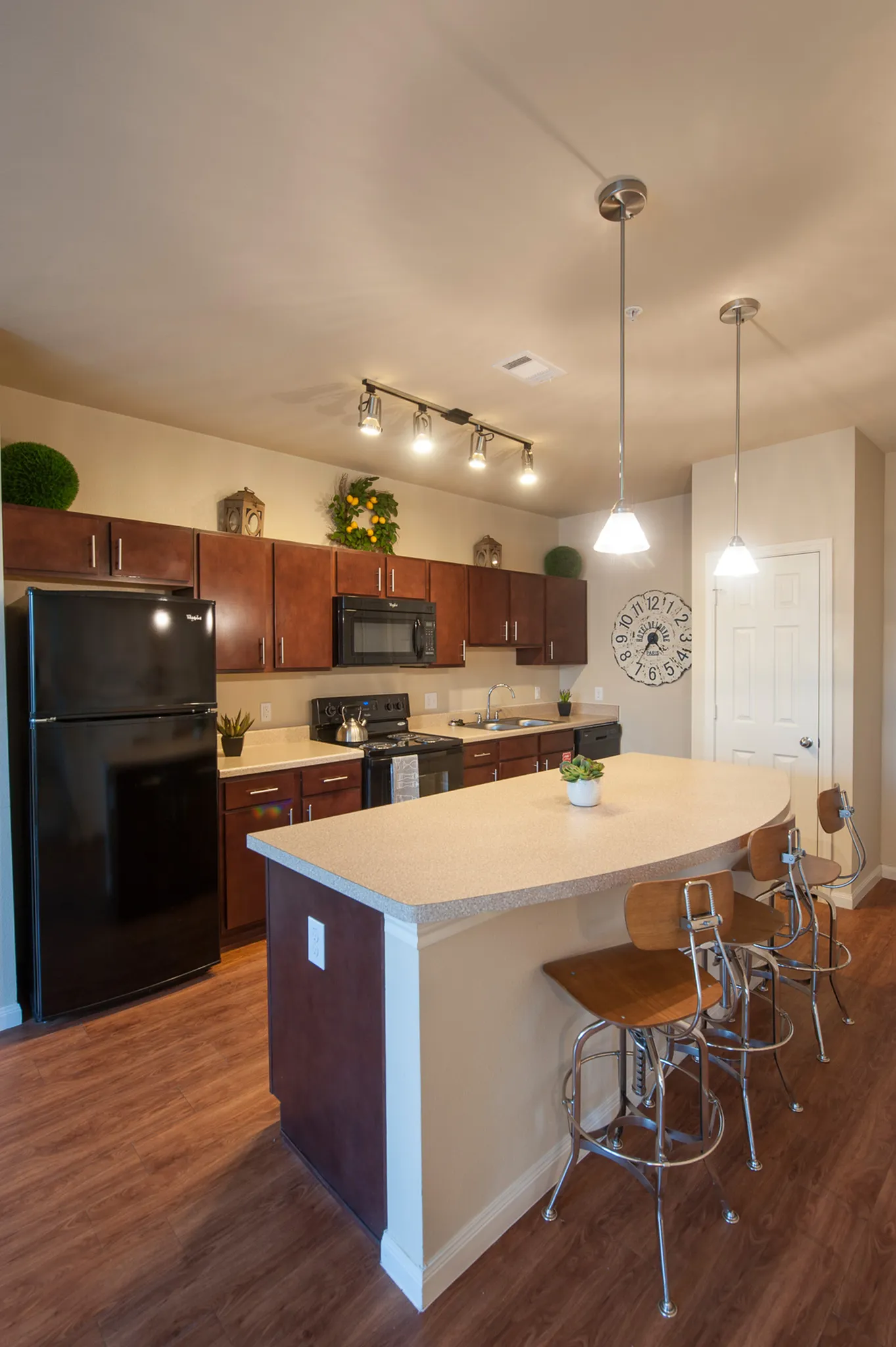 Chic kitchen with warm wood cabinetry, sleek countertops, and modern lighting, featuring a stylish island with bar seating.
