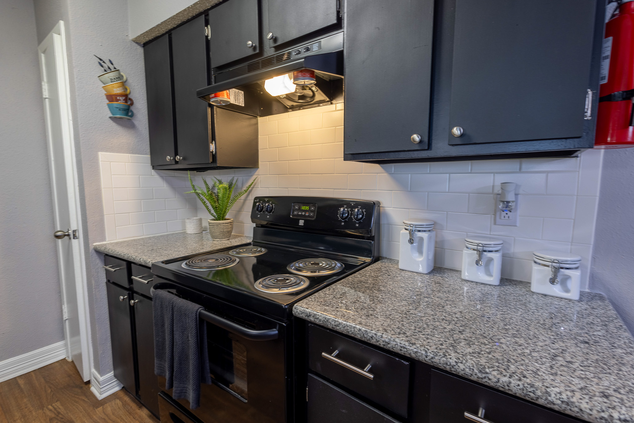 Modern kitchen with sleek black cabinets, granite countertops, and stylish white subway tile backsplash.