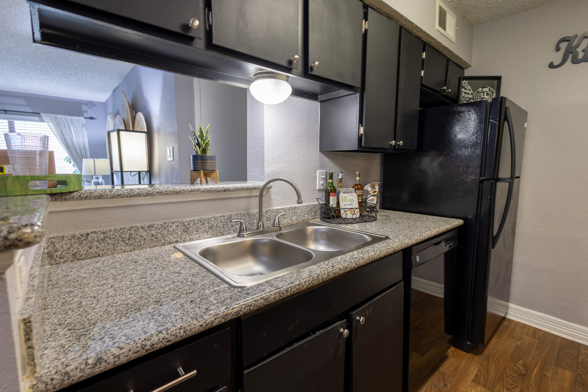 Elegant kitchen with sleek granite countertops, modern black cabinetry, and stainless steel sink, offering a sophisticated culinary space.