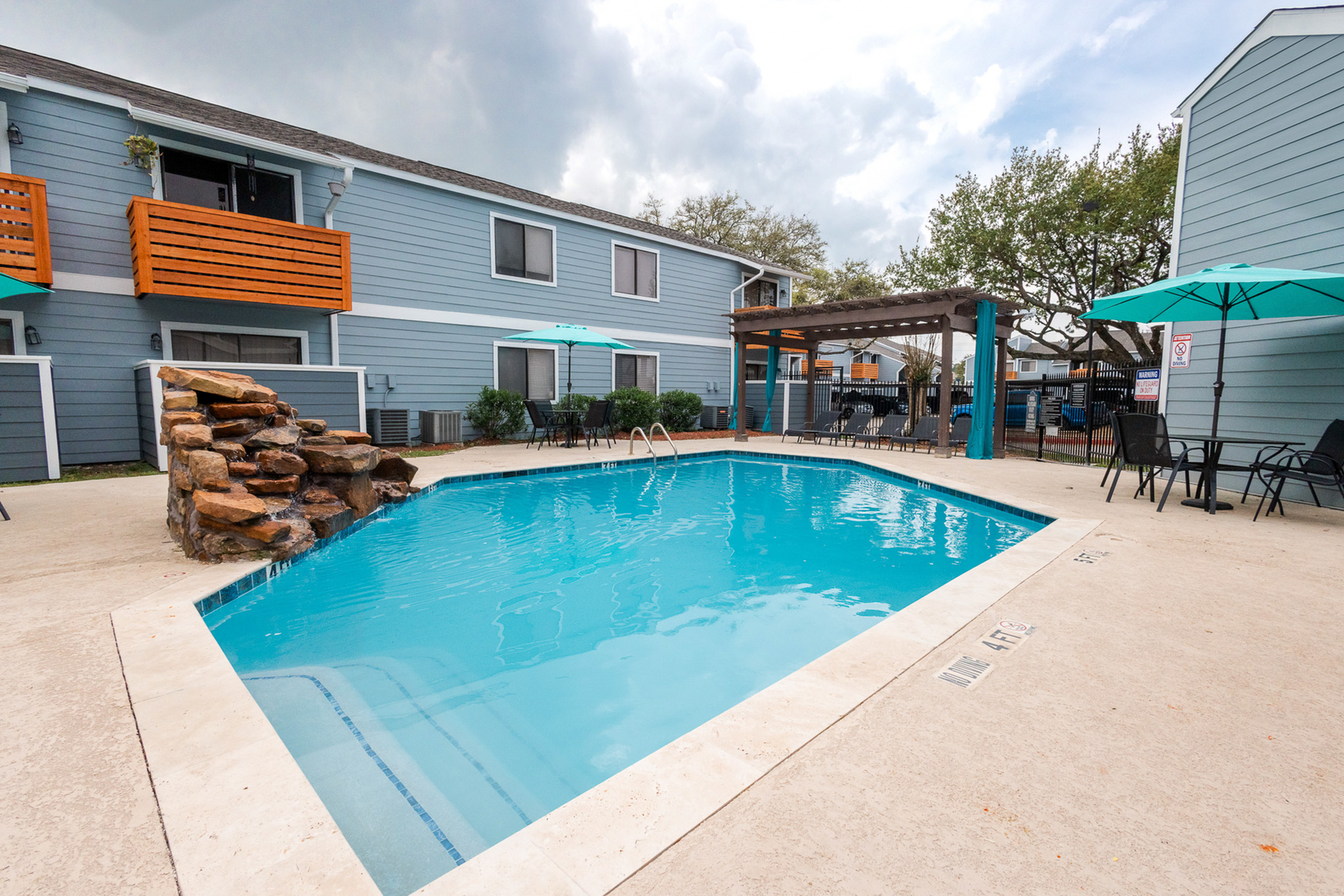 Swimming pool with lounge seating and shaded pergola at Waterchase Apartments in Humble, TX