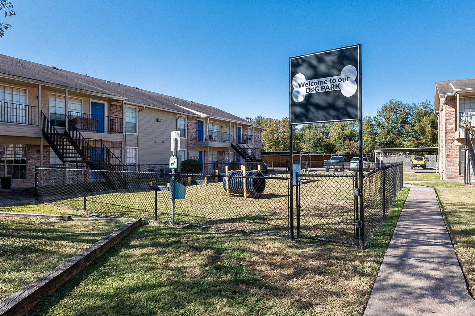 Charming apartment complex with cozy outdoor dog park and vibrant blue doors, perfect for pet-friendly living.