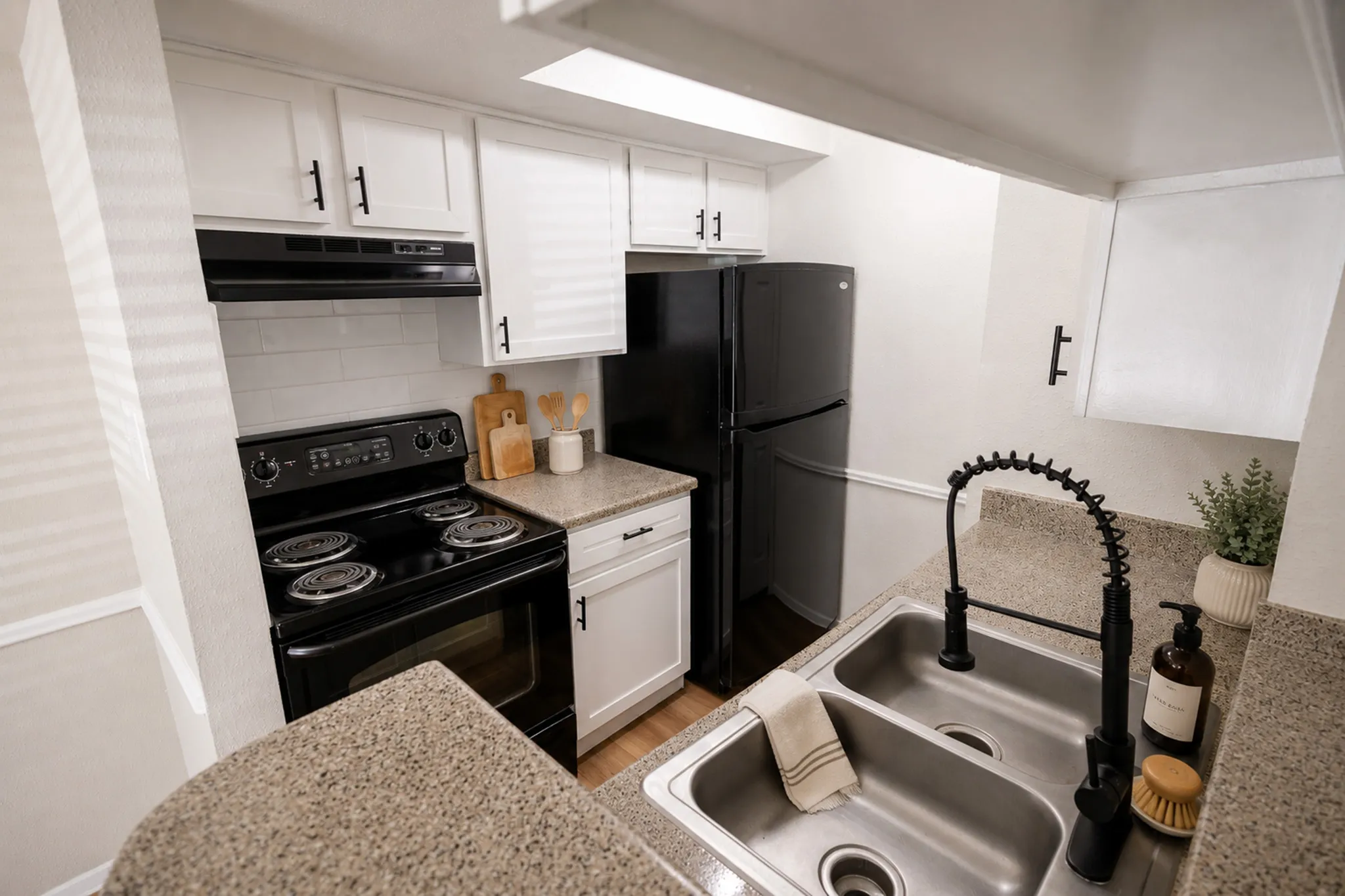 Modern kitchen with sleek black appliances, elegant granite countertops, and bright white cabinets, ideal for stylish cooking and entertaining.