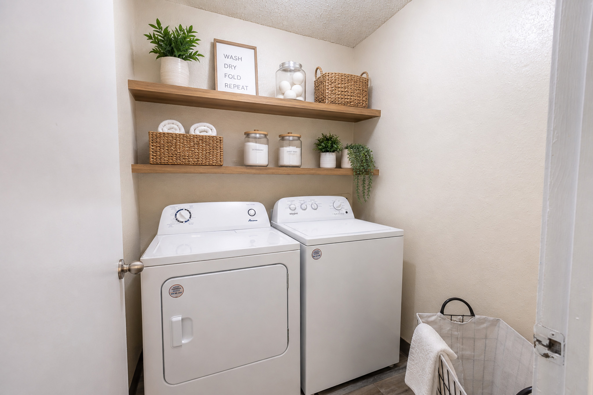 Chic laundry room featuring modern washer and dryer, elegant shelving with decor, and stylish storage solutions.
