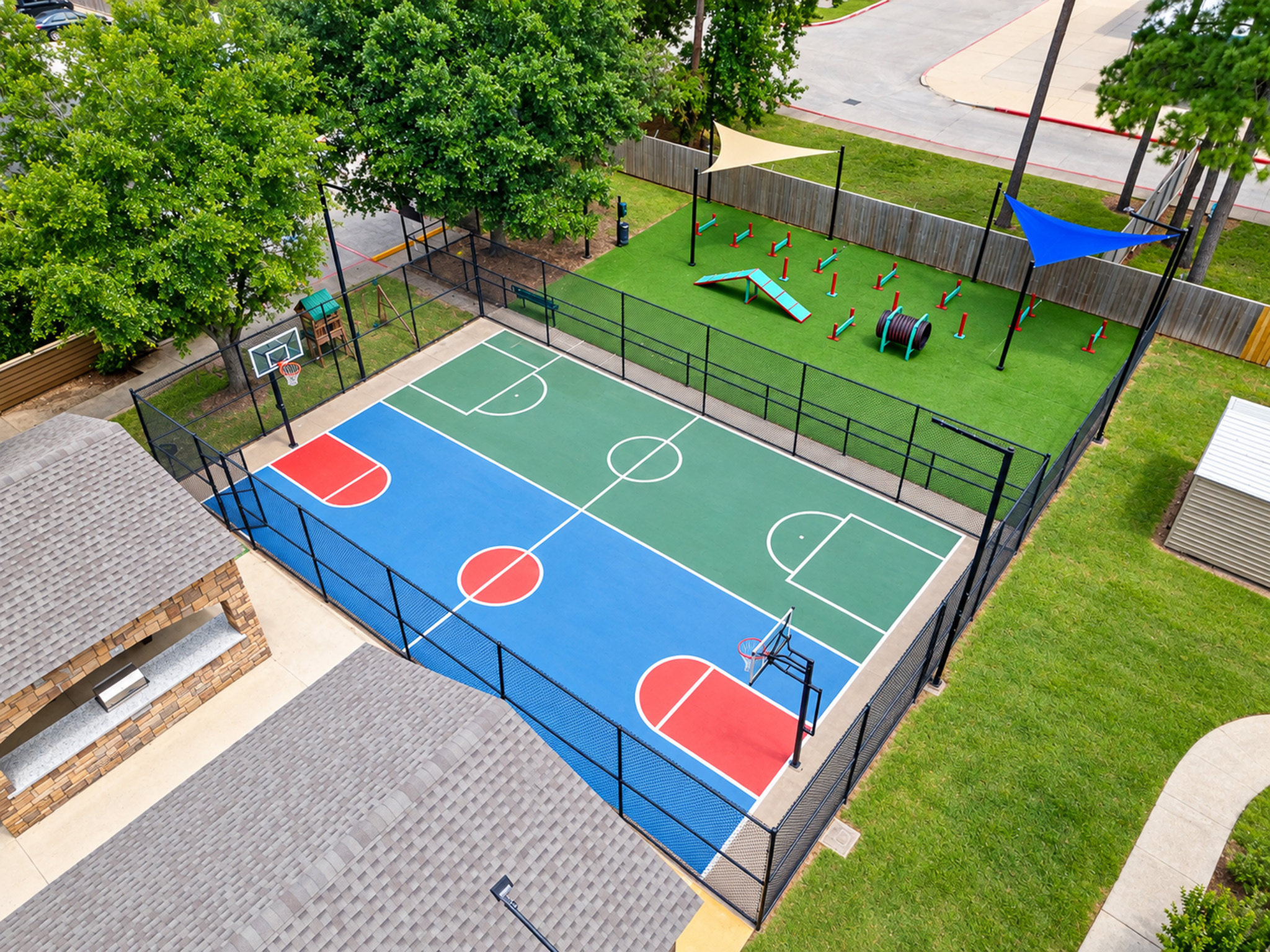 Vibrant recreational area featuring a well-maintained basketball court and colorful playground equipment, surrounded by lush greenery.