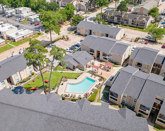 Aerial view of modern apartment complex with lush greenery, stylish swimming pool, and inviting outdoor seating area.
