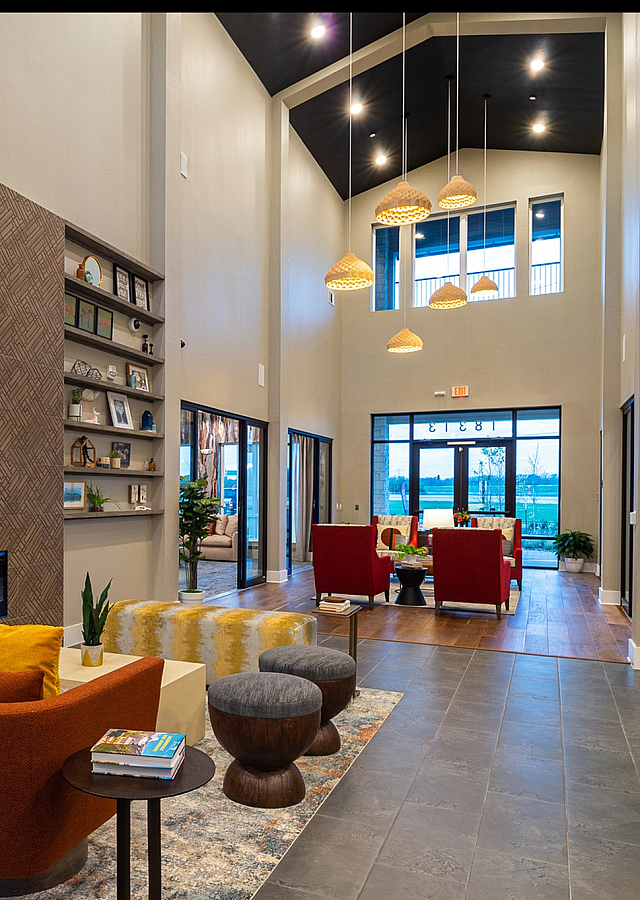 Modern and inviting lounge area featuring stylish orange chairs, elegant lighting, and a cozy fireplace, perfect for relaxation and social gatherings.