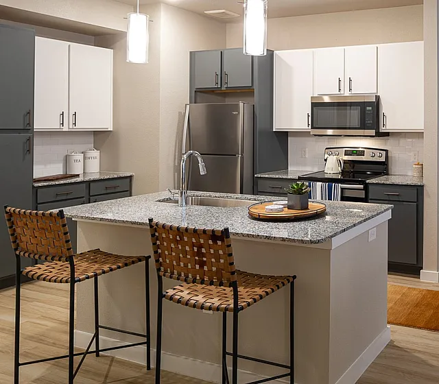 Modern open-concept kitchen and living room with sleek appliances, stylish island seating, and chic decor.