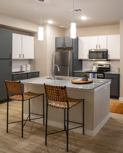 Modern kitchen with sleek cabinetry, granite countertops, stylish pendant lighting, and woven bar stools.