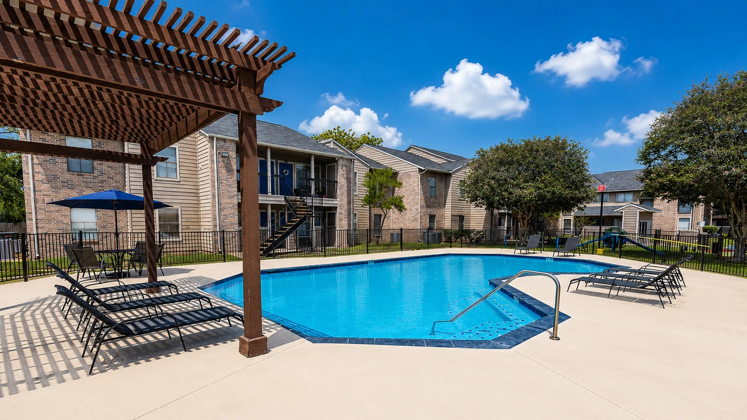 Apartment community swimming pool with lounge chairs at Green Meadows Apartments in Houston TX
