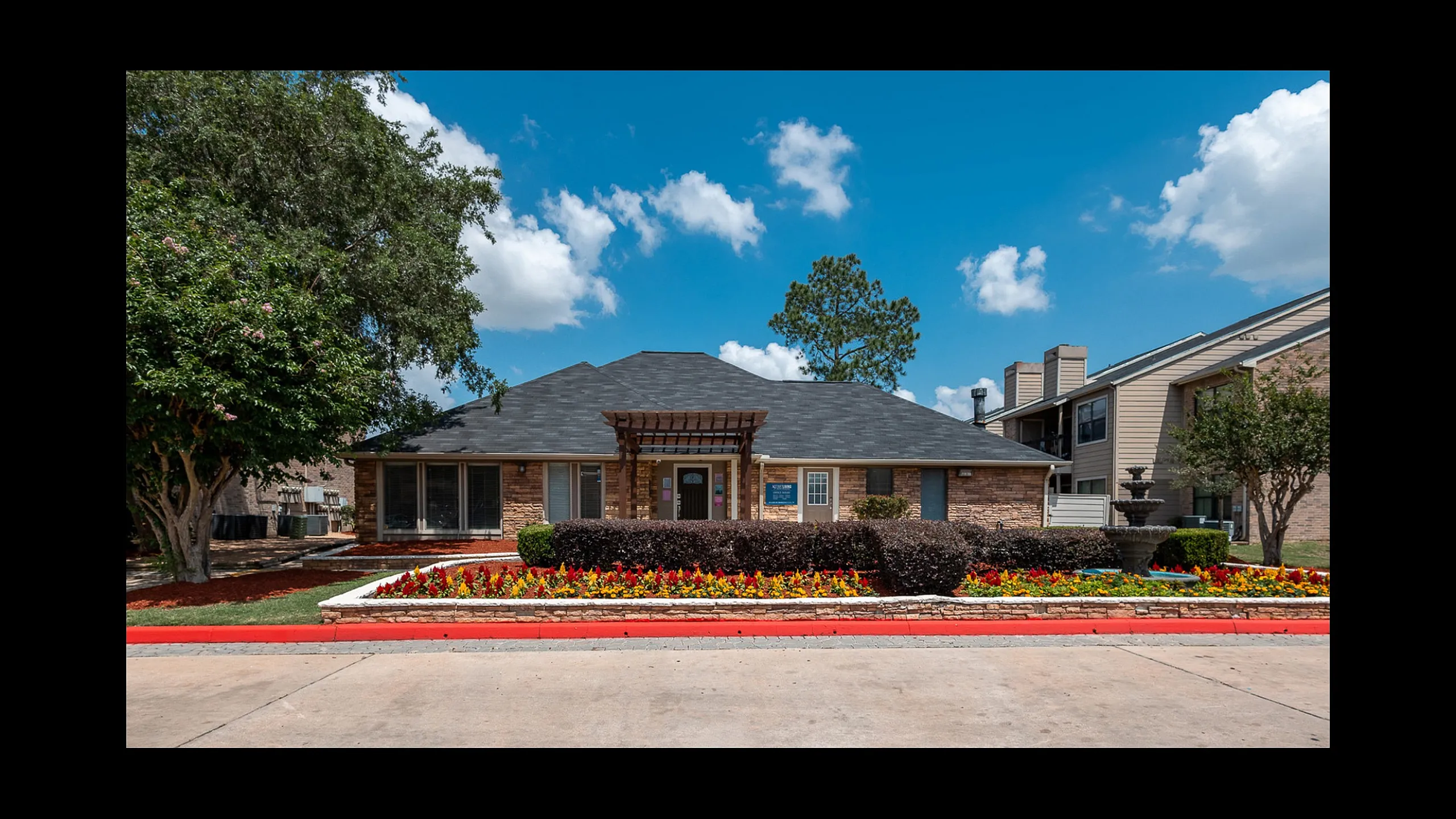 Leasing office exterior with landscaped entrance at Green Meadows Apartments in Houston TX