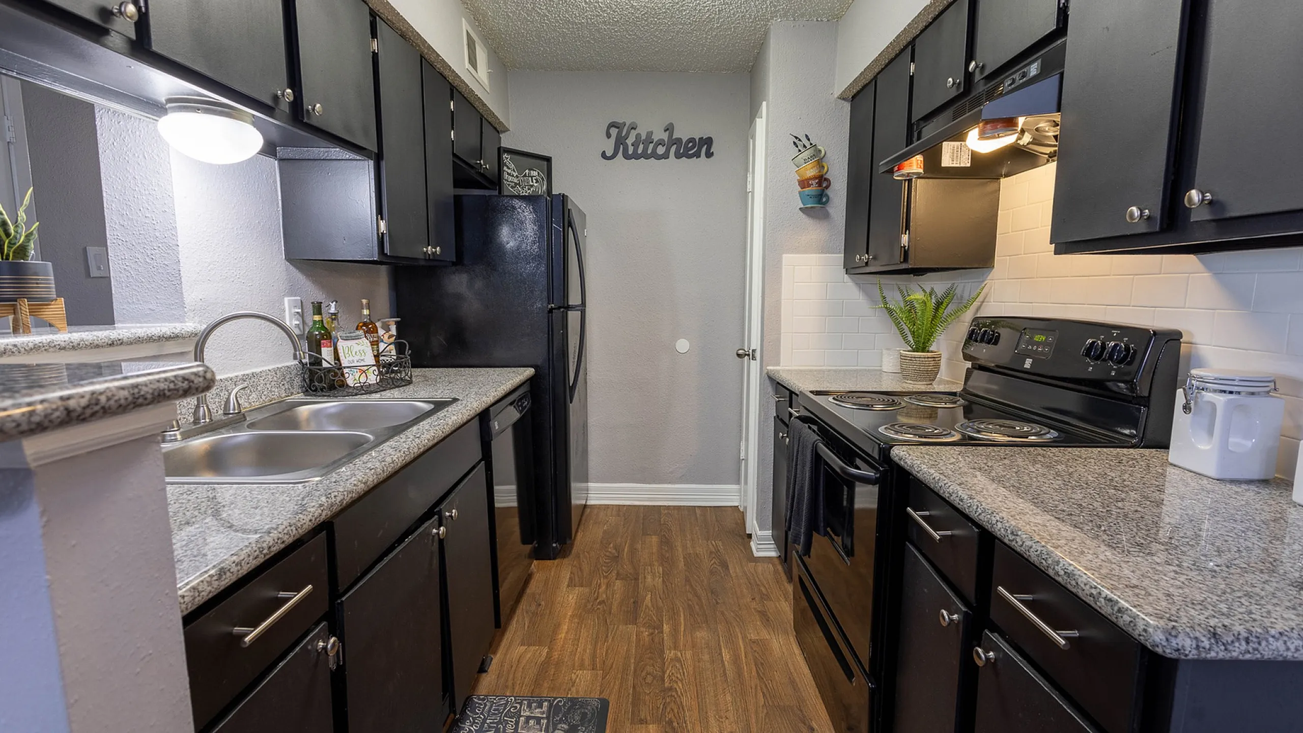 Modern kitchen with sleek dark cabinetry, polished granite countertops, and stainless steel appliances, highlighting a cozy and efficient culinary space.