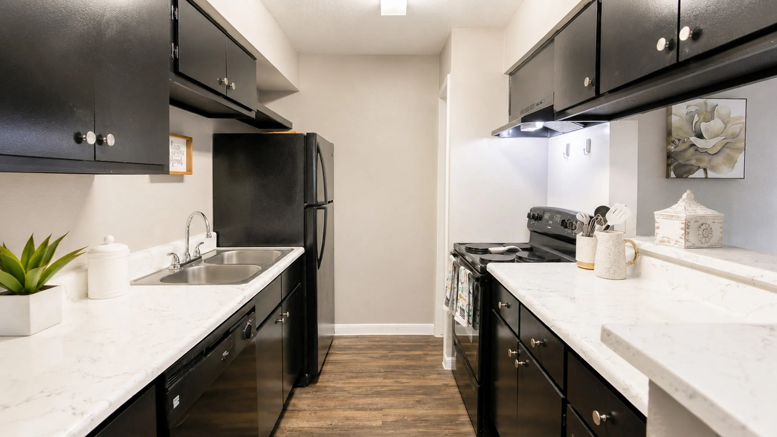 Updated galley kitchen with black appliances and modern countertops at Newport Oaks Apartments in Alvin TX