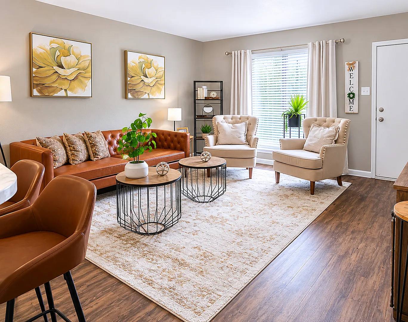 Inviting living room with stylish brown leather sofa, modern coffee tables, cozy beige armchairs, and vibrant wall art, bathed in natural light.