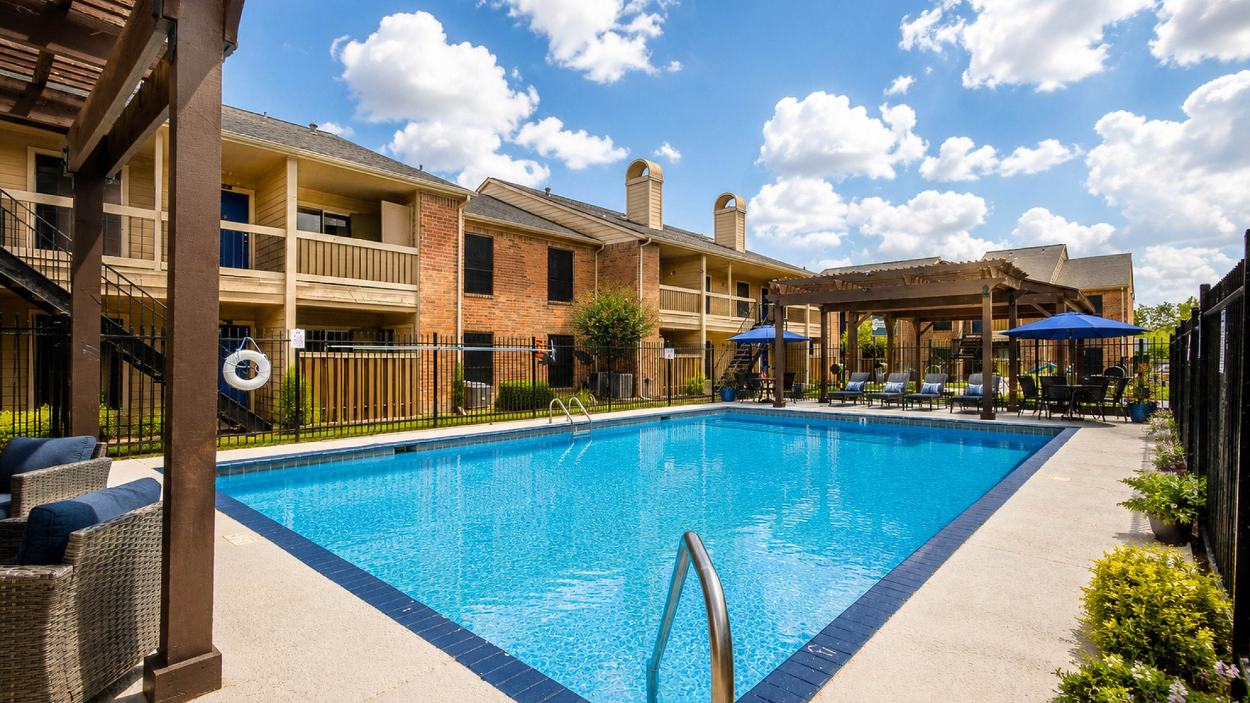Inviting outdoor pool area with cozy seating and vibrant umbrella shades, perfect for relaxation and leisure activities at a charming apartment complex.