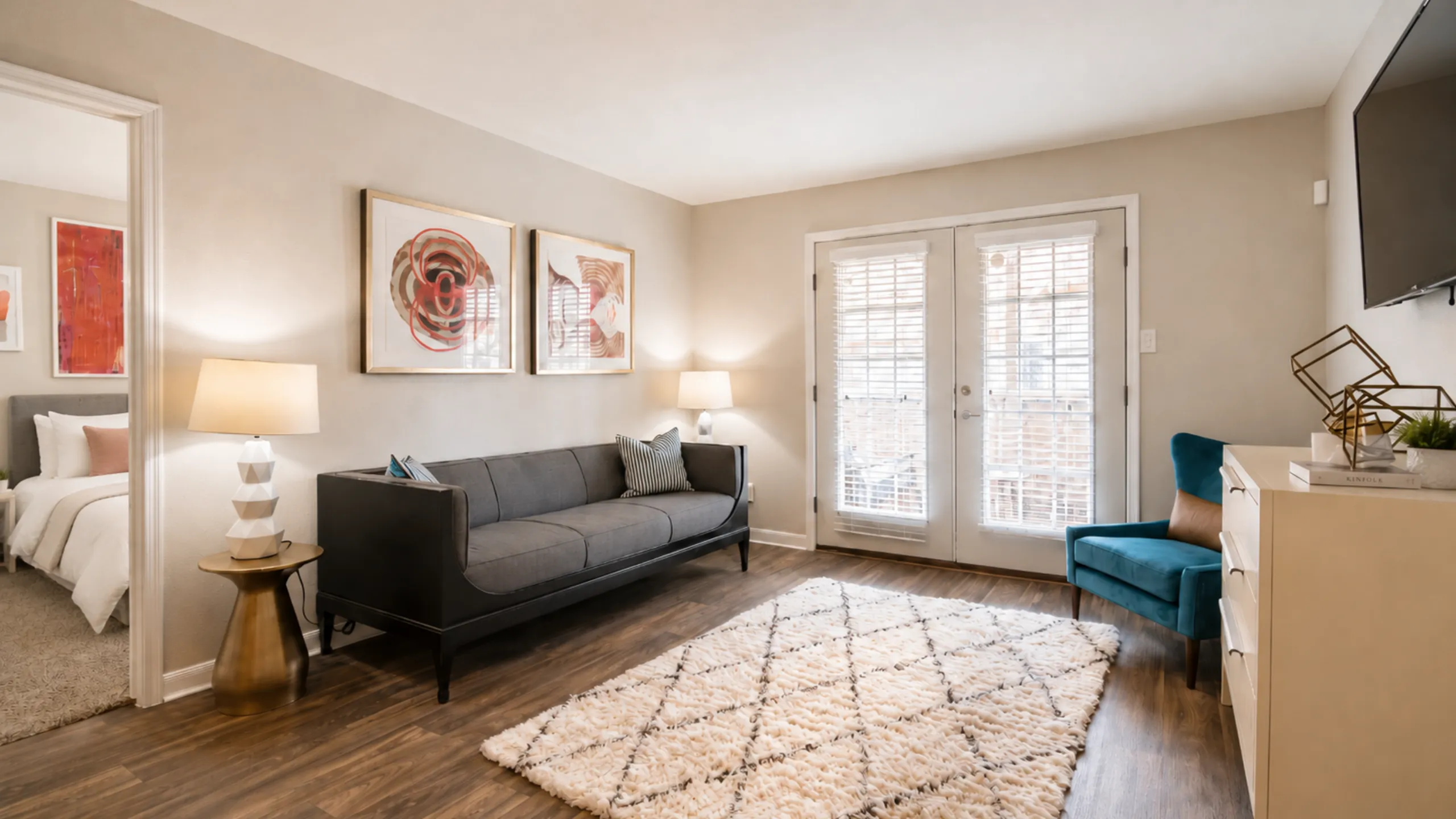 Chic living room with modern sofa, plush armchair, and bright natural light from French doors.