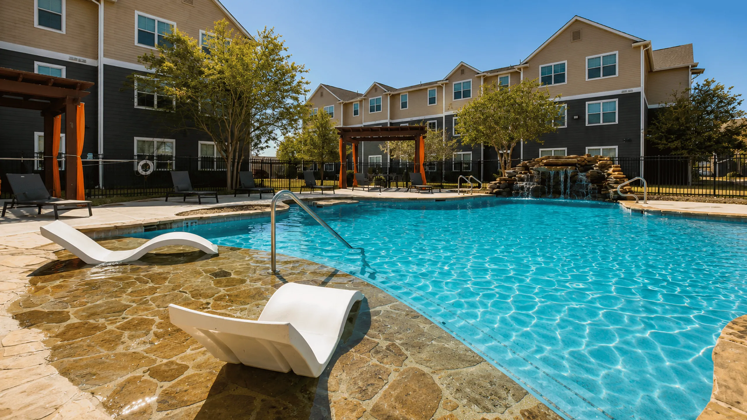 Resort-style swimming pool at Oak Tree Apartments in Kingsville, TX, surrounded by comfortable poolside seating and landscaping.