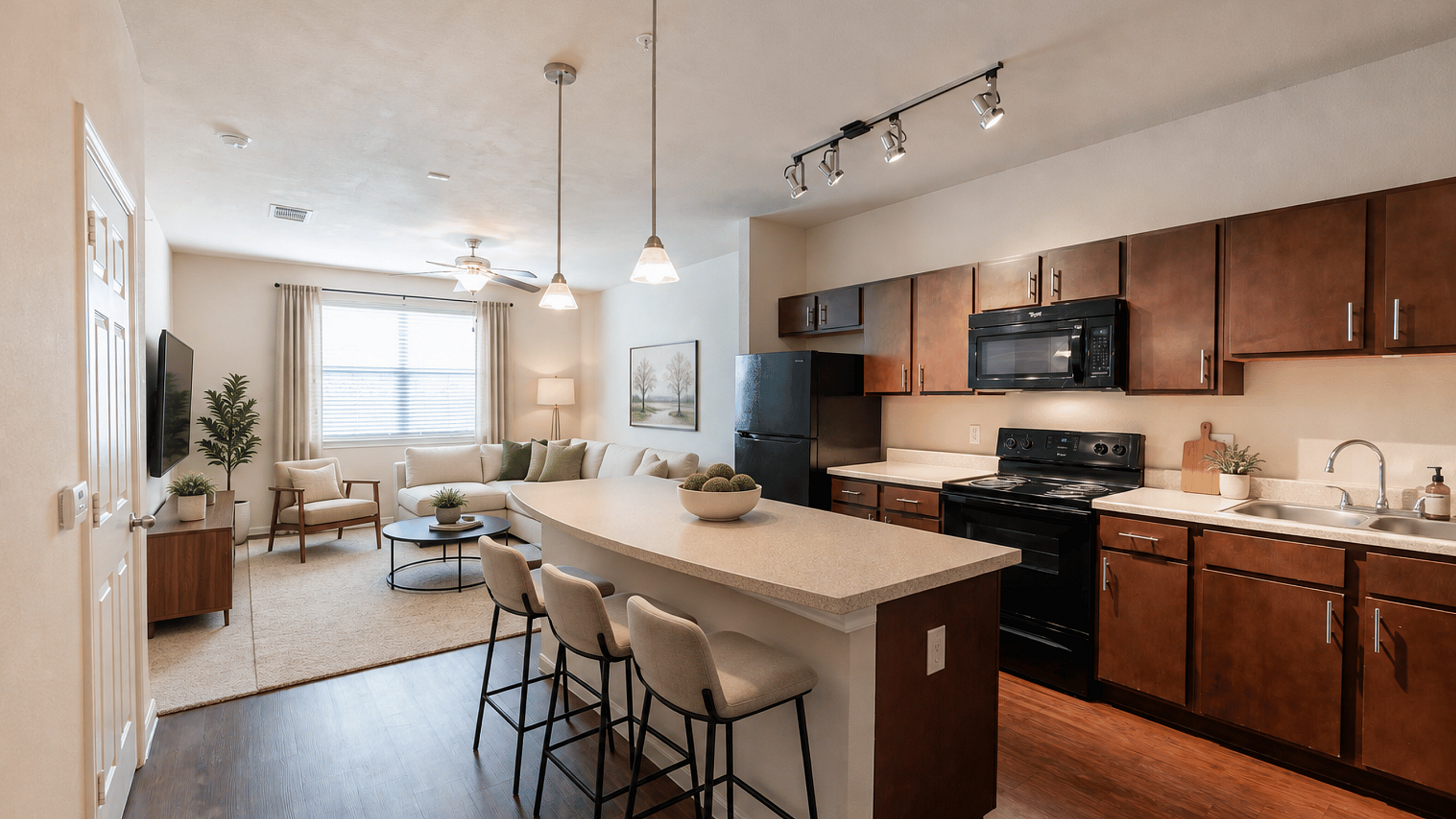 Open-concept kitchen and living room at Oak Tree Apartments in Kingsville, TX, featuring dark wood cabinetry, breakfast bar seating and modern furnishings.
