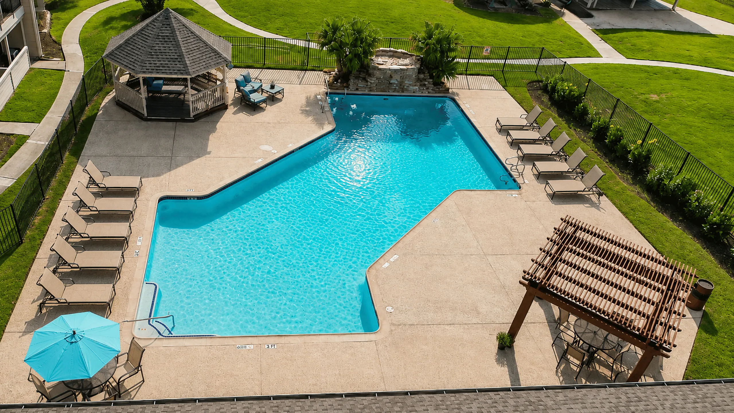 Aerial view of the swimming pool with organized lounge seating, gazebo, umbrella and shaded seating areas at The Reserve on Garth in Baytown, TX.