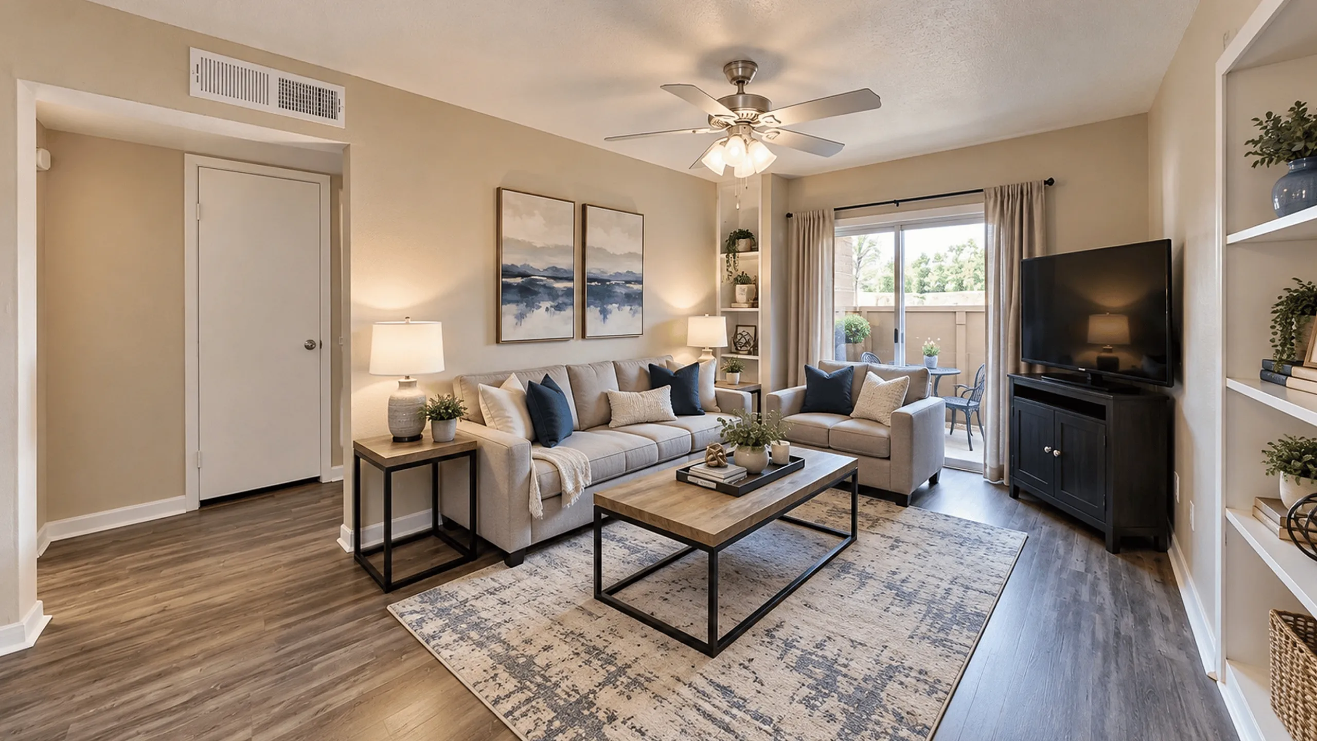 Bright apartment living room with neutral furnishings, blue accents, wood-style flooring and patio access at Parkside Apartments.