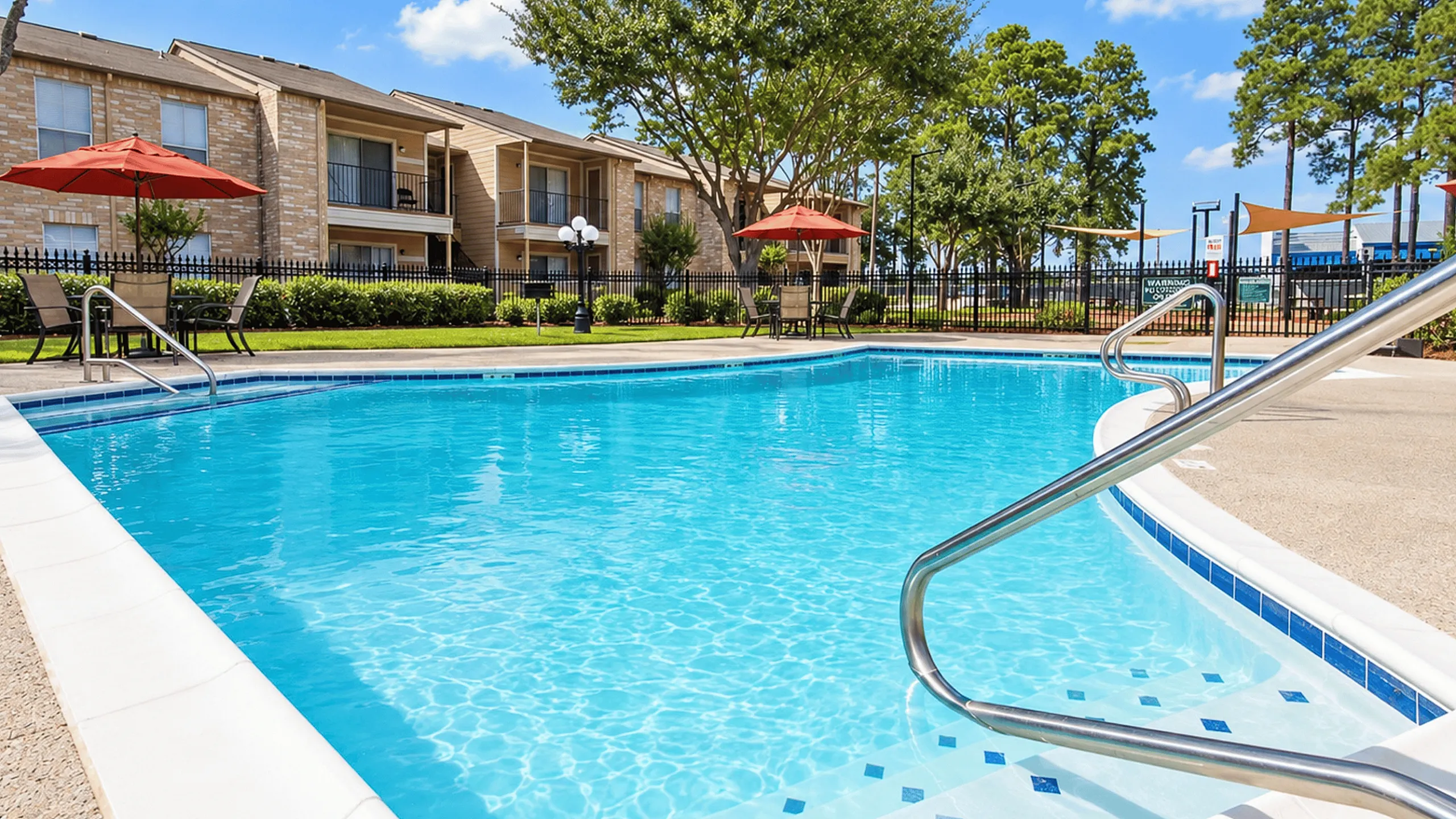 Close view of the Parkside Apartments swimming pool with entry steps, handrails and surrounding patio.