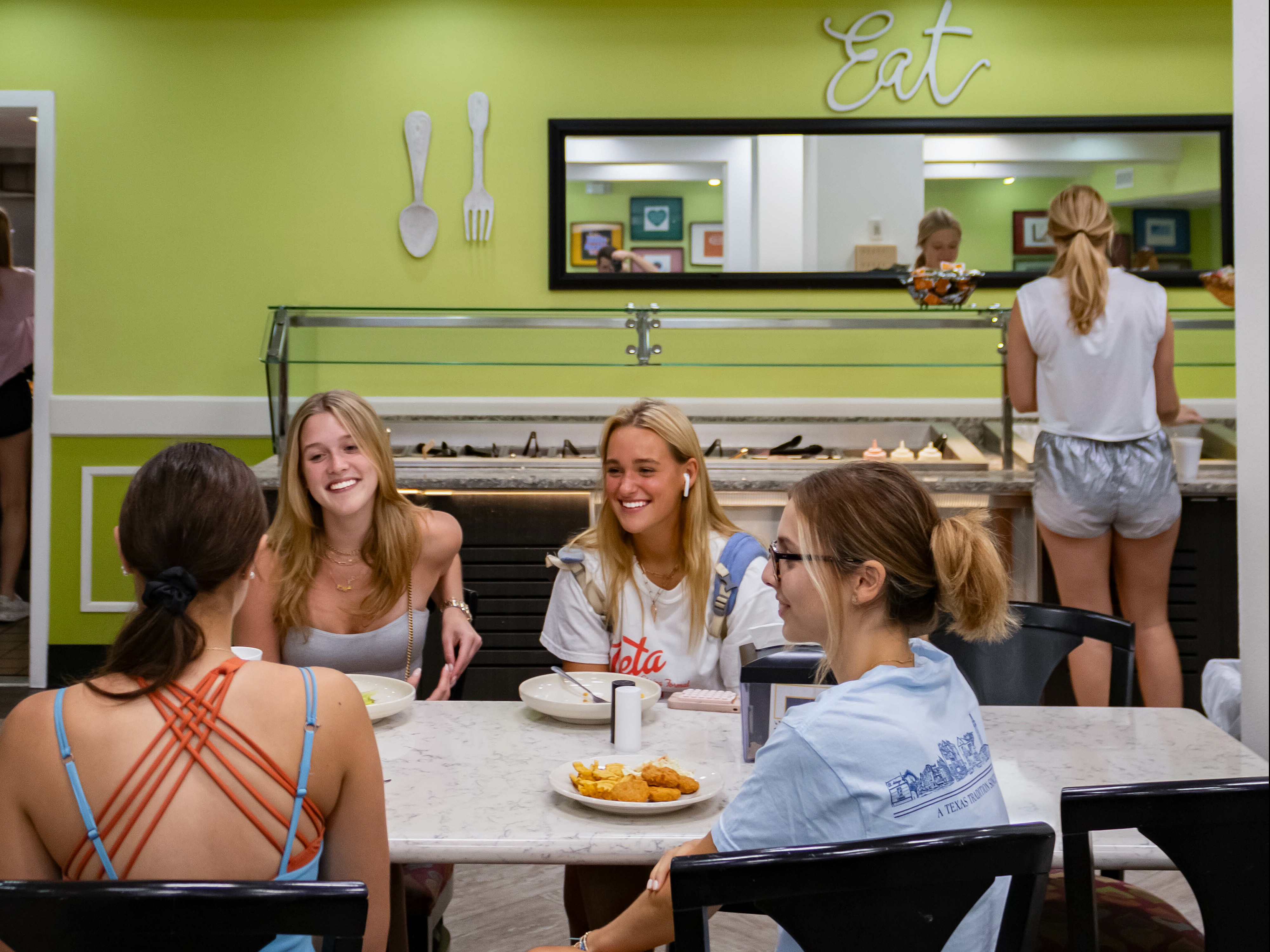 Vibrant dining area with cheerful people enjoying a meal together at a stylish table in a brightly painted room.