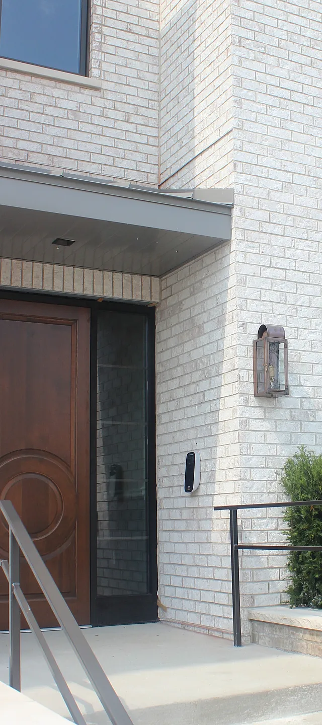 Elegant apartment entrance with modern brick facade, secure railing, and vibrant greenery for curb appeal.
