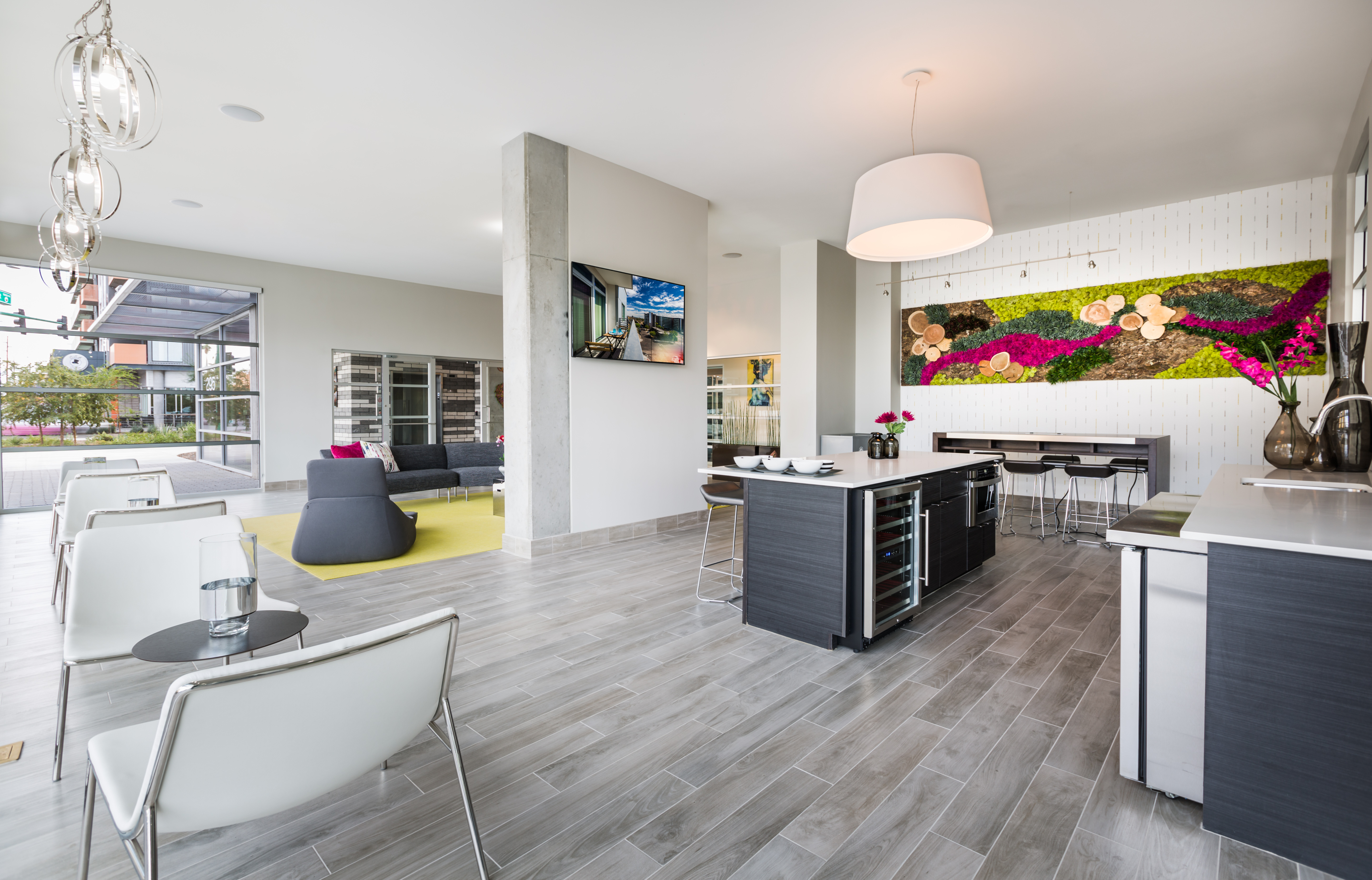Modern open-concept apartment featuring a stylish kitchen island, chic lounge area, and vibrant wall art under elegant lighting.