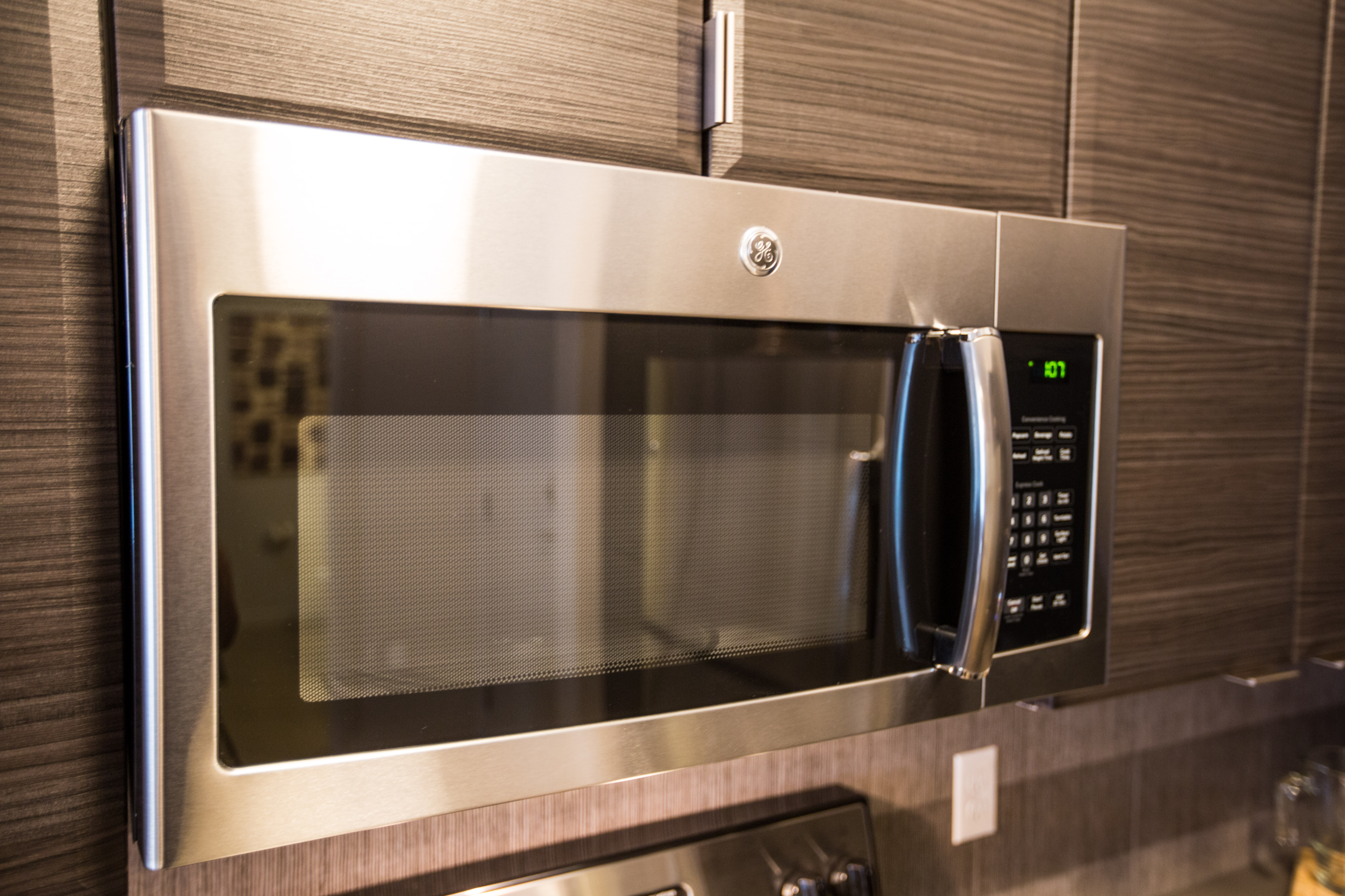 Modern kitchen with sleek stainless steel microwave, integrated into elegant dark wood cabinetry for a sophisticated look.