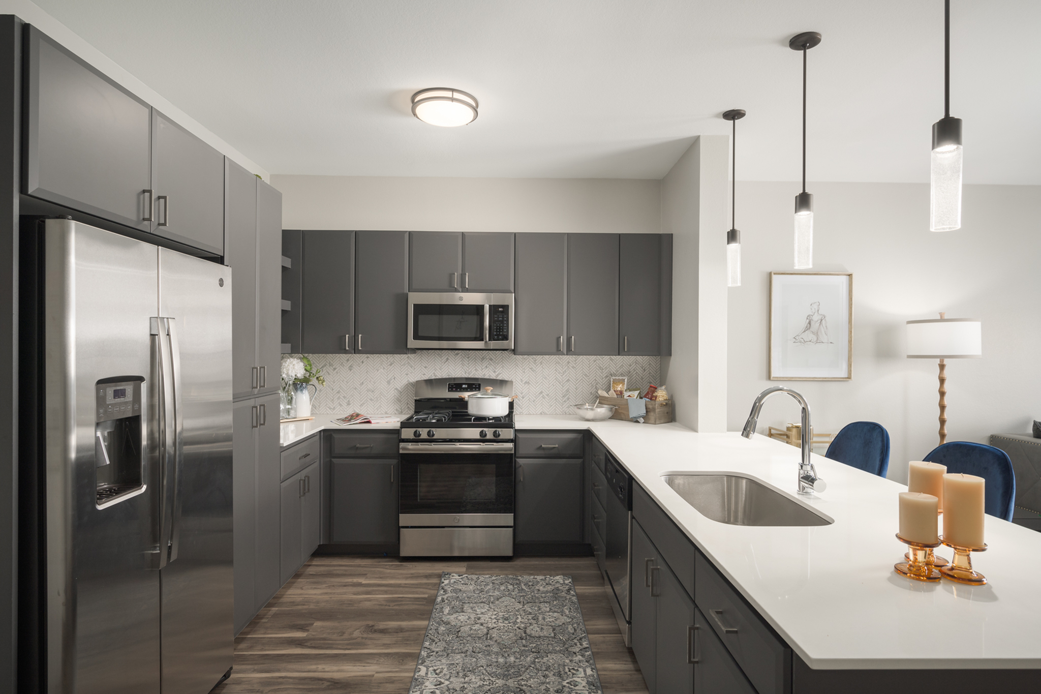 Sleek modern kitchen with stainless steel appliances, elegant dark cabinets, and a stylish breakfast bar illuminated by chic pendant lights.
