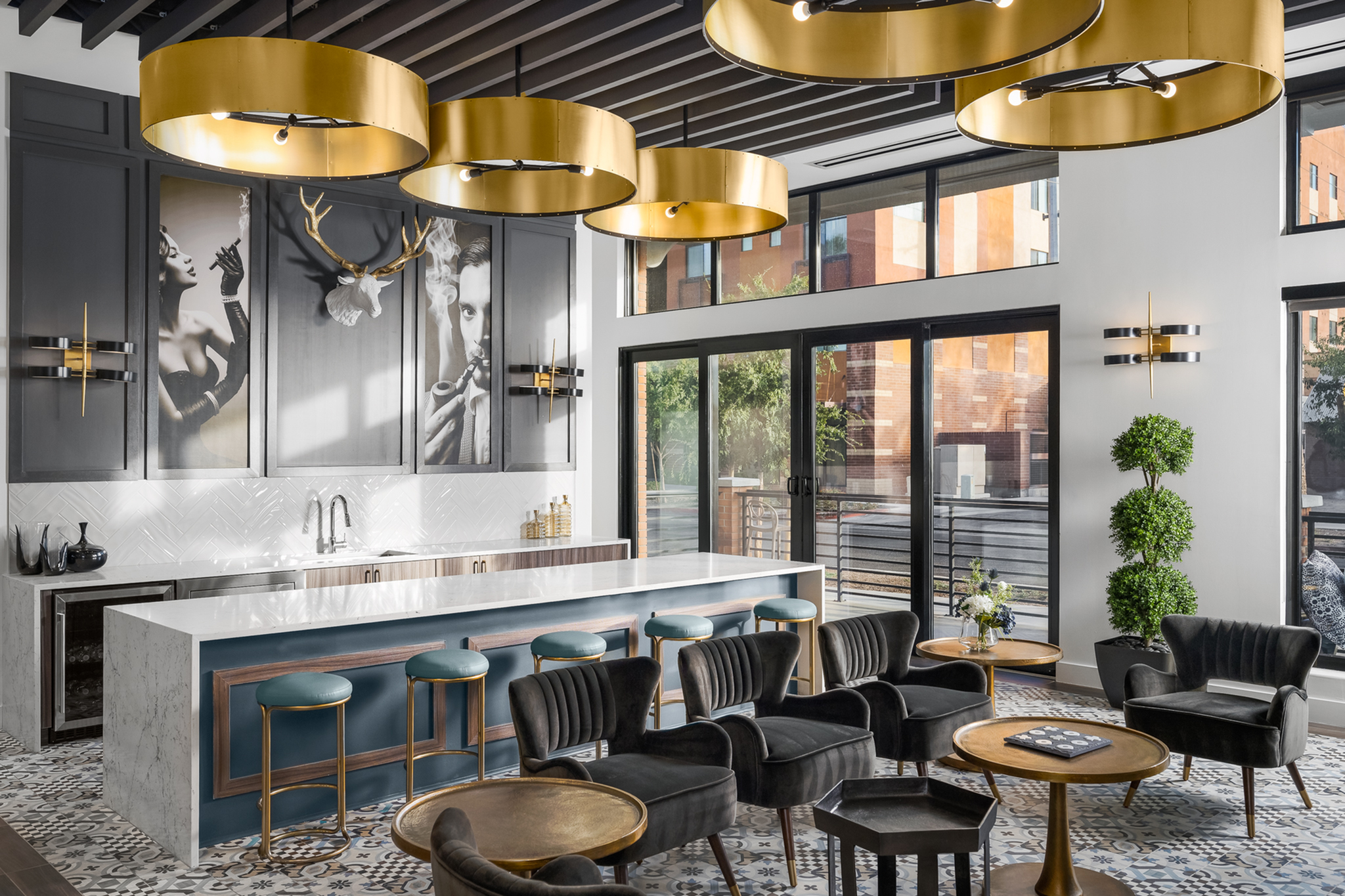 Luxurious and modern apartment lounge featuring chic gold lighting, a sleek marble island, and elegant black seating, enhanced by vibrant wall art and expansive windows.