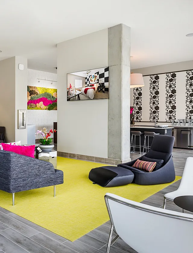 Modern, spacious living area with sleek hardwood floors, vibrant yellow accents, comfortable seating, and elegant lighting, ideal for social gatherings and relaxation.