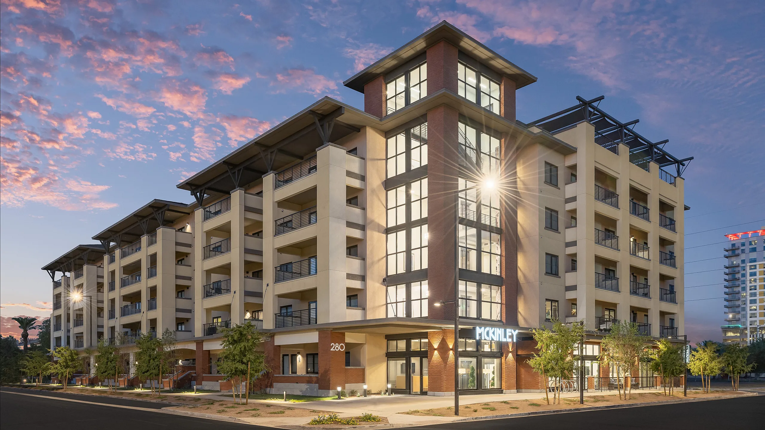 Modern multi-story apartment building with stylish balconies and contemporary architecture at sunset.