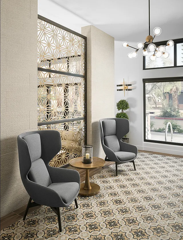 Elegant lobby area with stylish gray armchairs, intricate patterned floor tiles, and modern lighting, offering a chic and inviting ambiance.