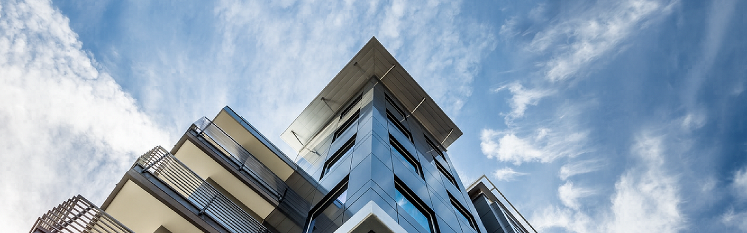 Modern architectural design of a high-rise apartment building with sleek balconies against a clear blue sky.