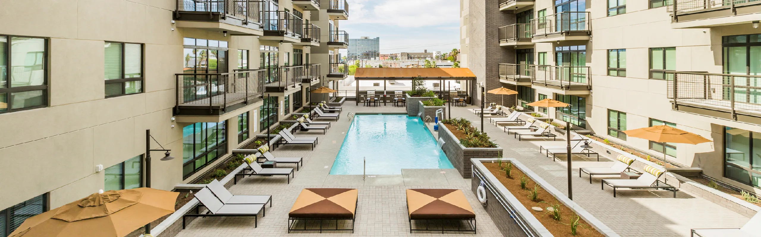 Chic urban apartment complex with a central swimming pool, surrounded by modern lounging areas and stylish balconies.