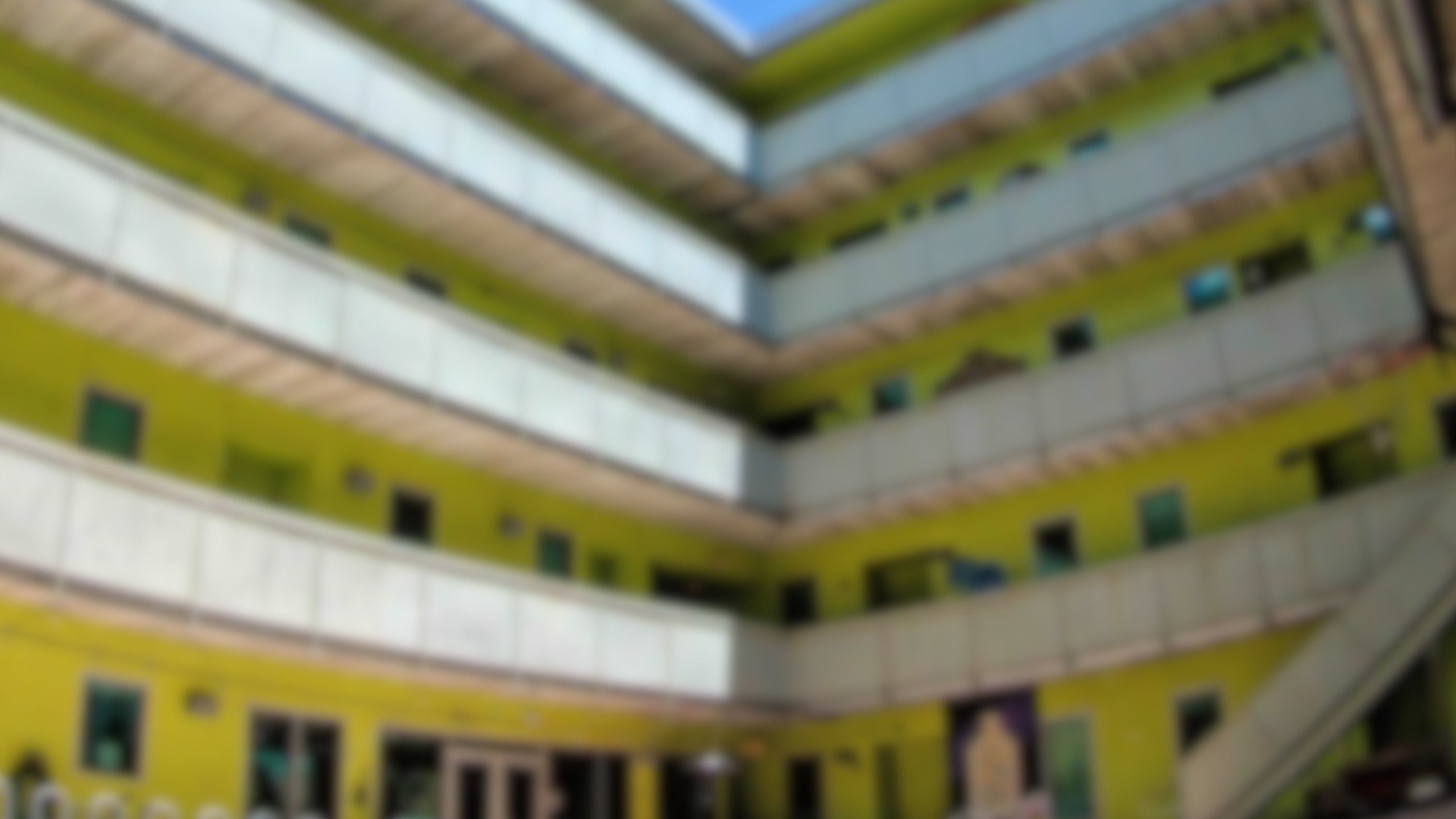Vibrant residential building with bright green exterior and multiple balconies, showcasing modern urban living.