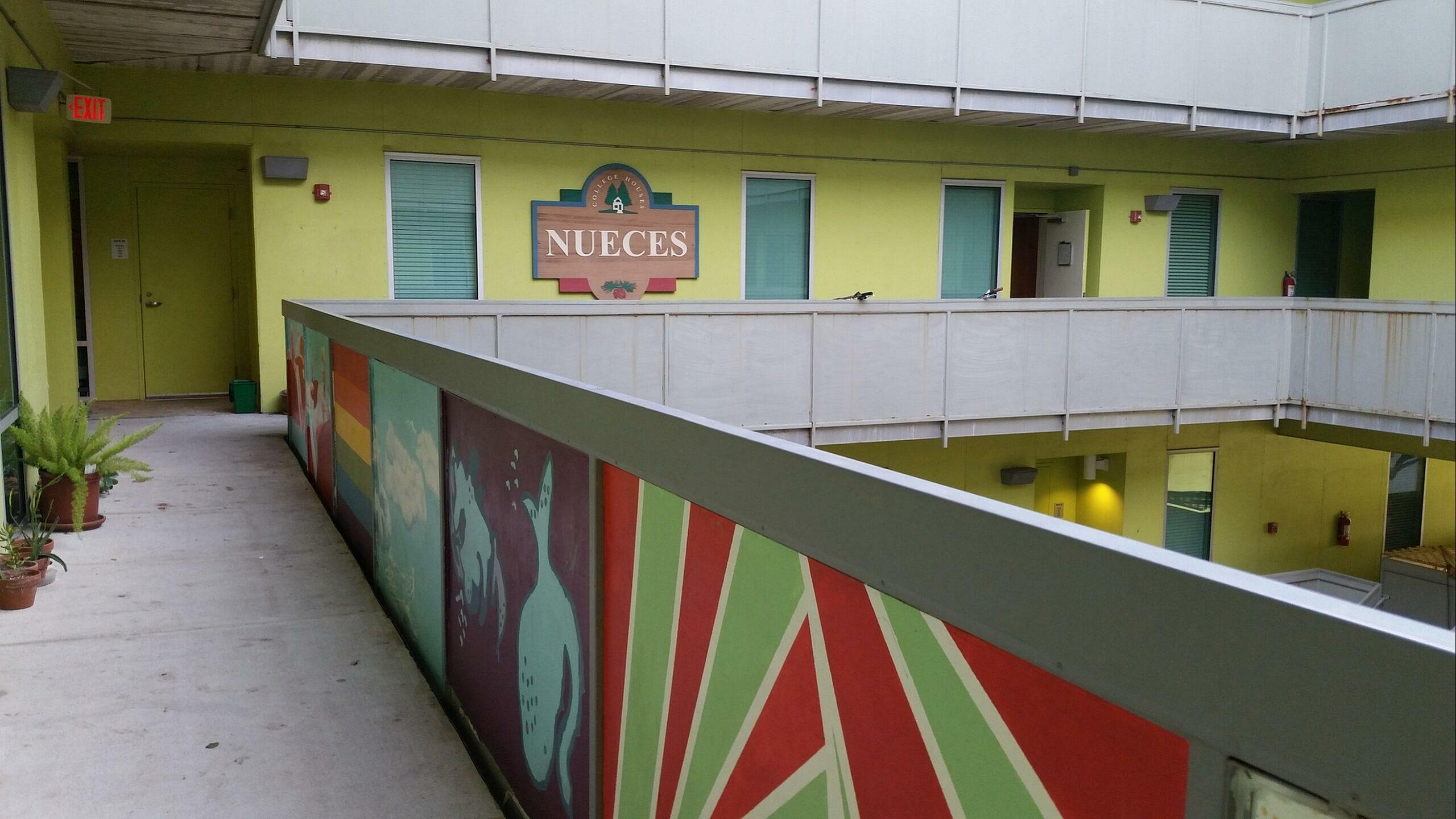 Vibrant apartment corridor with colorful murals and plant decorations, highlighting the welcoming atmosphere of Nueces property.