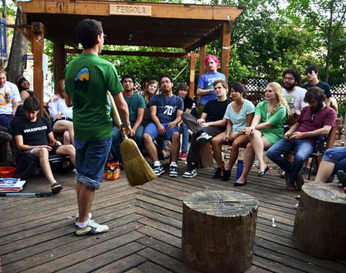 Dynamic outdoor gathering on a charming wooden deck with diverse group of people interacting under a cozy pergola.