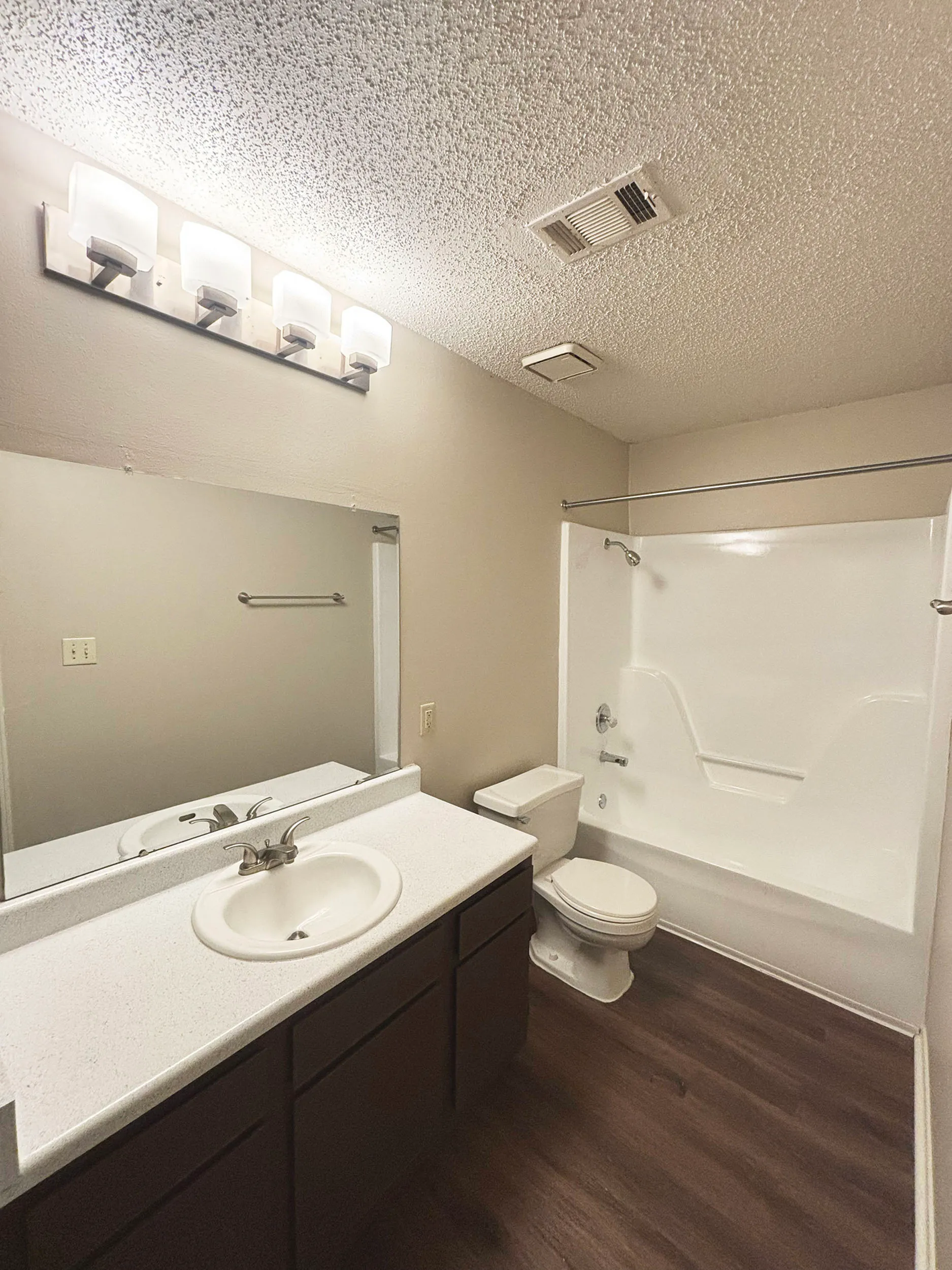 Contemporary bathroom with elegant lighting, polished countertop, and modern shower-tub combo.