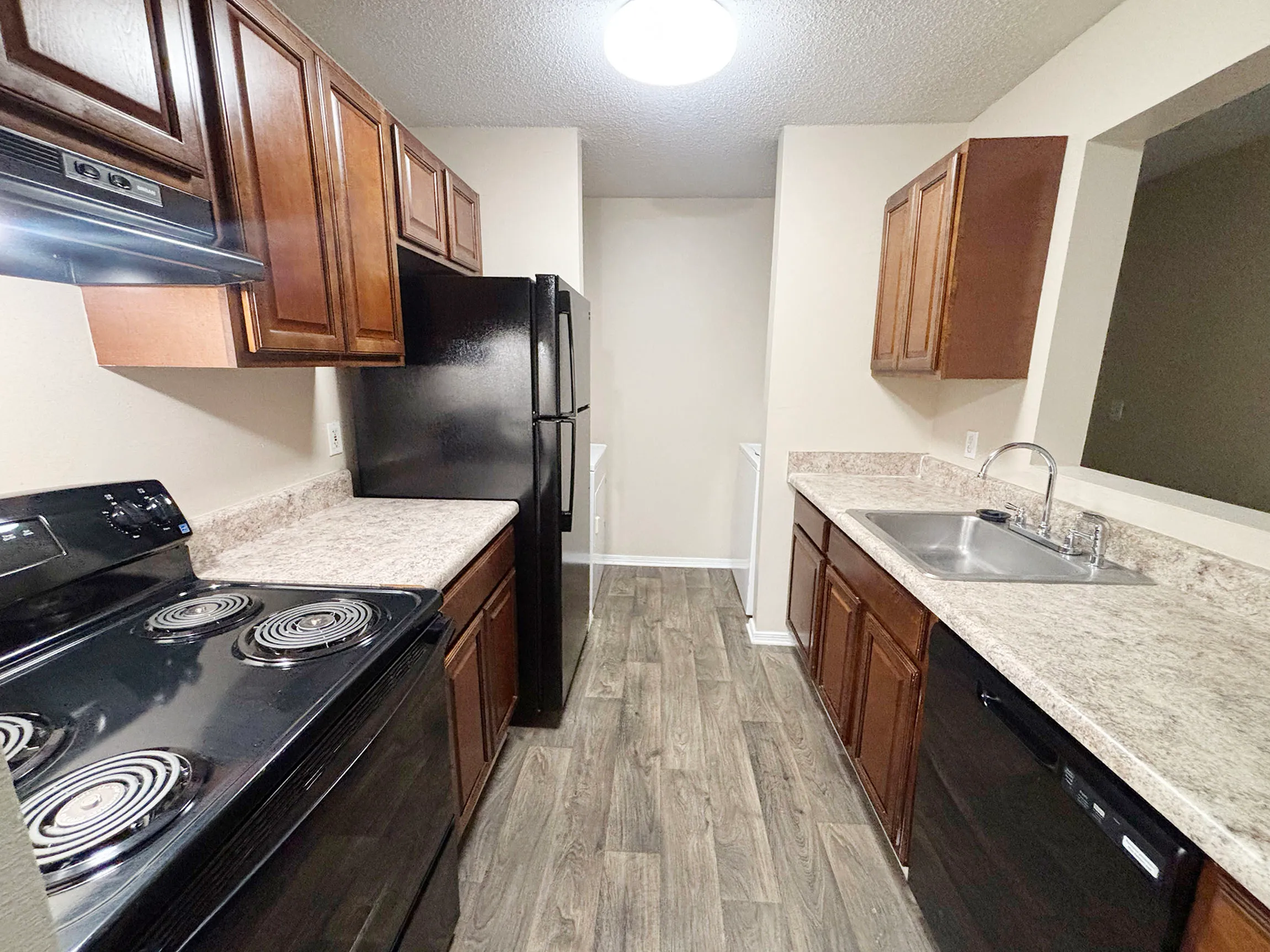 Modern kitchen with sleek black appliances, wooden cabinetry, and spacious countertops, perfect for culinary enthusiasts.